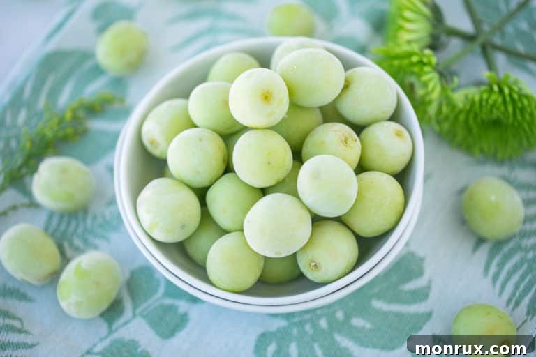 A beautifully presented bowl of frozen grapes, vibrant green and frosted, ready for a healthy snack.