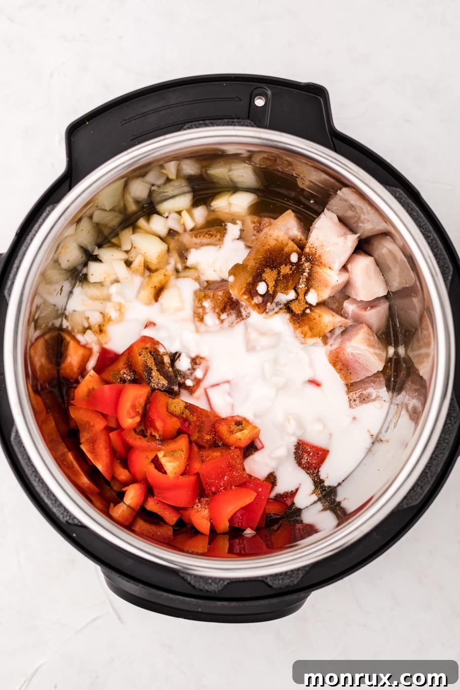 Instant Pot filled with mahi mahi, bell peppers, onions, and coconut milk, ready for cooking.