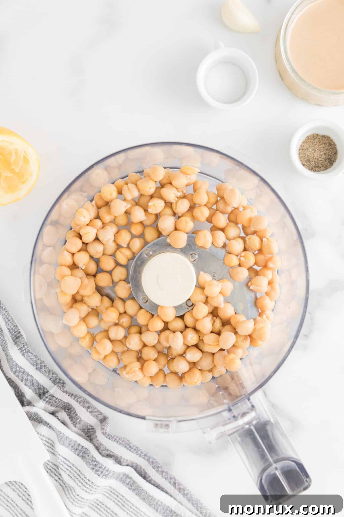 Rinsed and drained canned chickpeas, ready for blending, placed neatly in the bowl of a food processor.