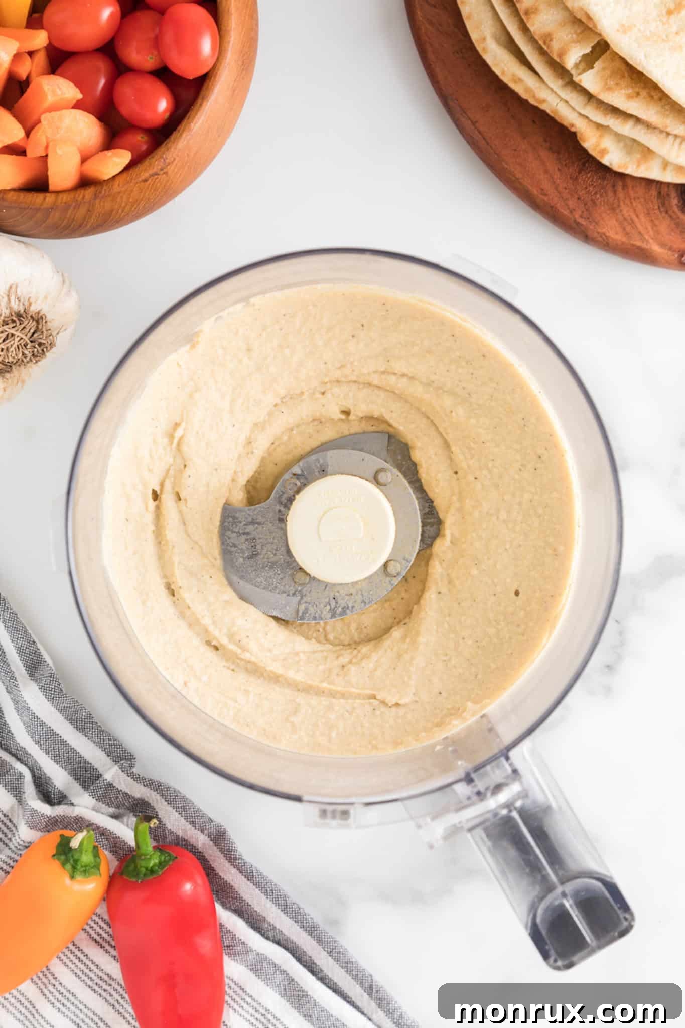 The finished homemade oil-free hummus, perfectly blended to a smooth, creamy consistency, resting in the bowl of a food processor, ready to be served.