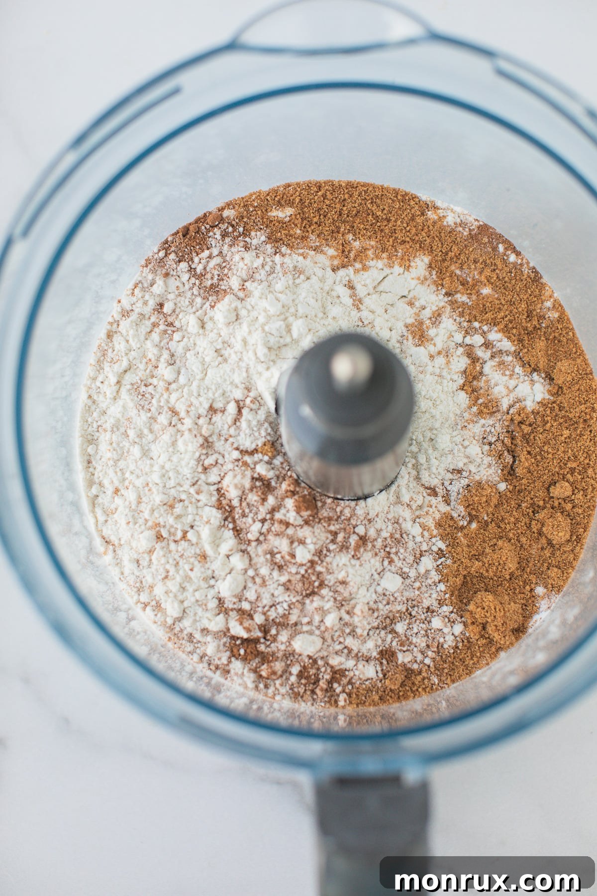 Dry ingredients for scones, including gluten-free flour and spices, measured and ready in the bowl of a food processor.