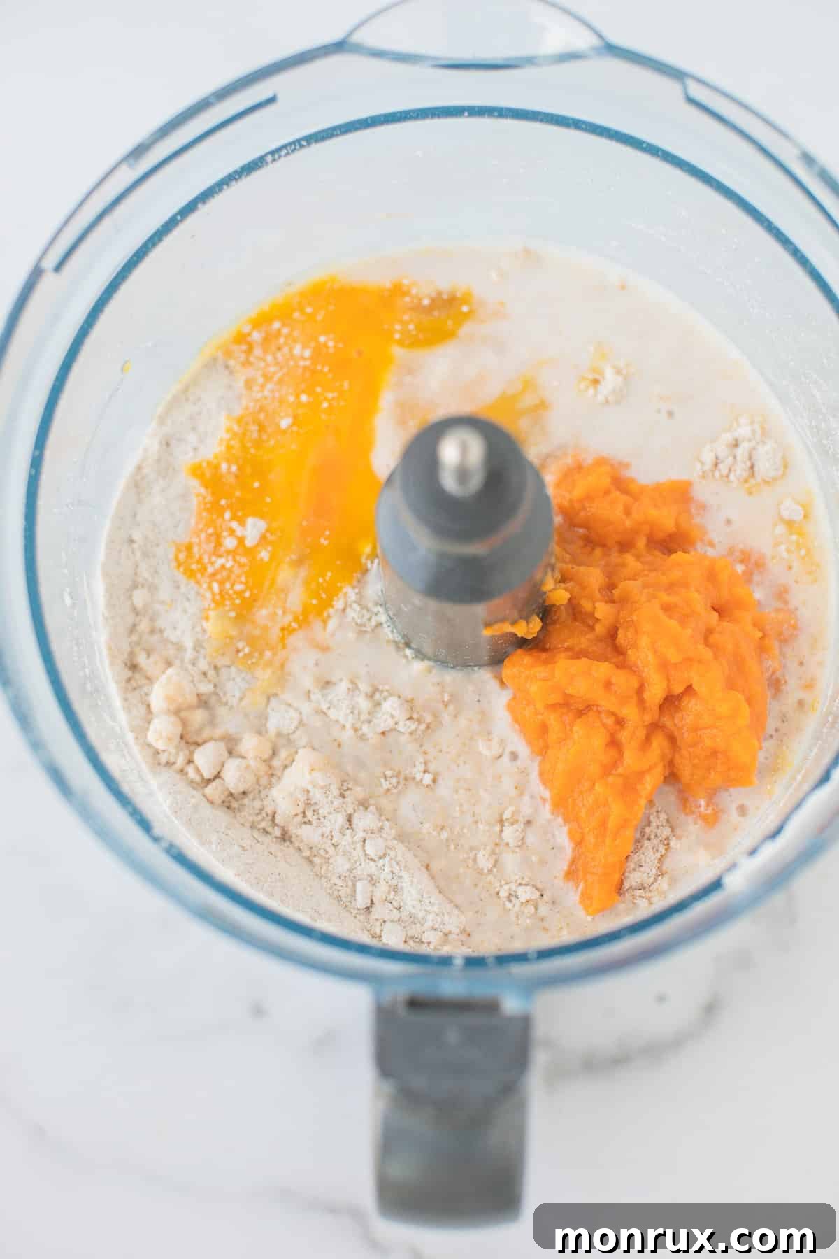 The food processor with wet ingredients added to the dry mixture, forming a smooth batter for gluten-free scones.