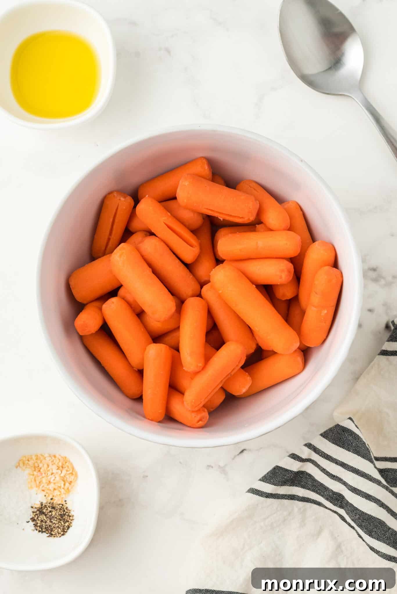 Drained baby carrots in a mixing bowl, ready for seasoning.