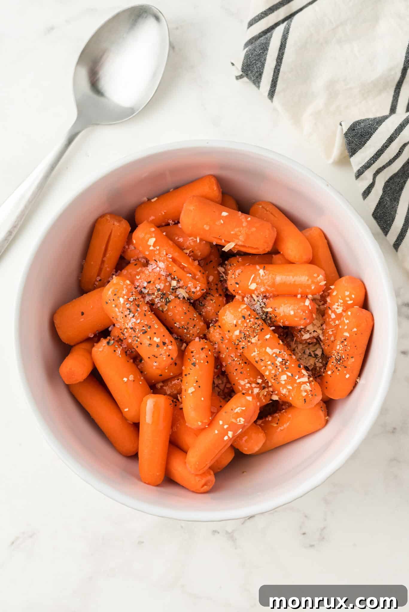Baby carrots seasoned with oil and spices in a bowl.