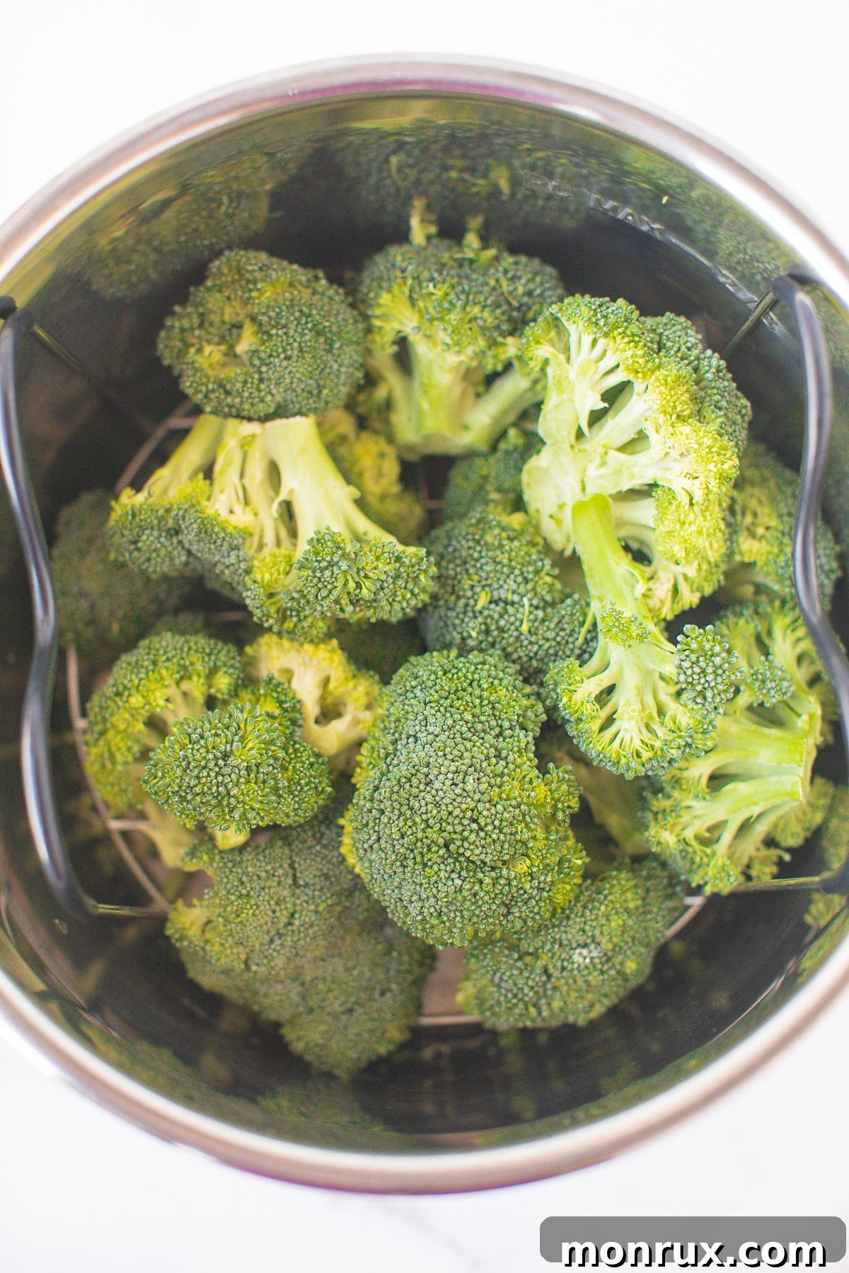 Broccoli florets arranged on a trivet inside an Instant Pot, with water visible at the bottom.