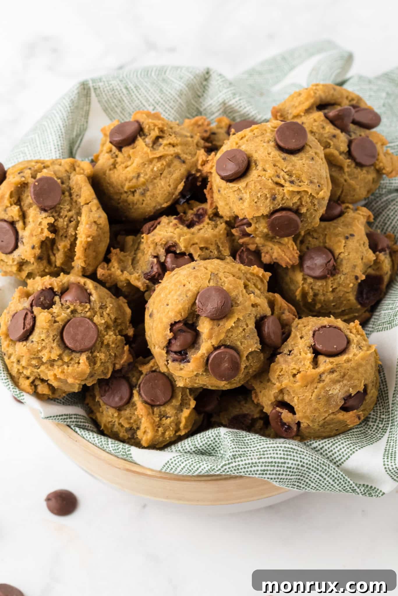 A charming basket filled with golden-brown vegan pumpkin chocolate chip cookies, artfully arranged on a rustic wooden table, evoking a warm autumnal ambiance.