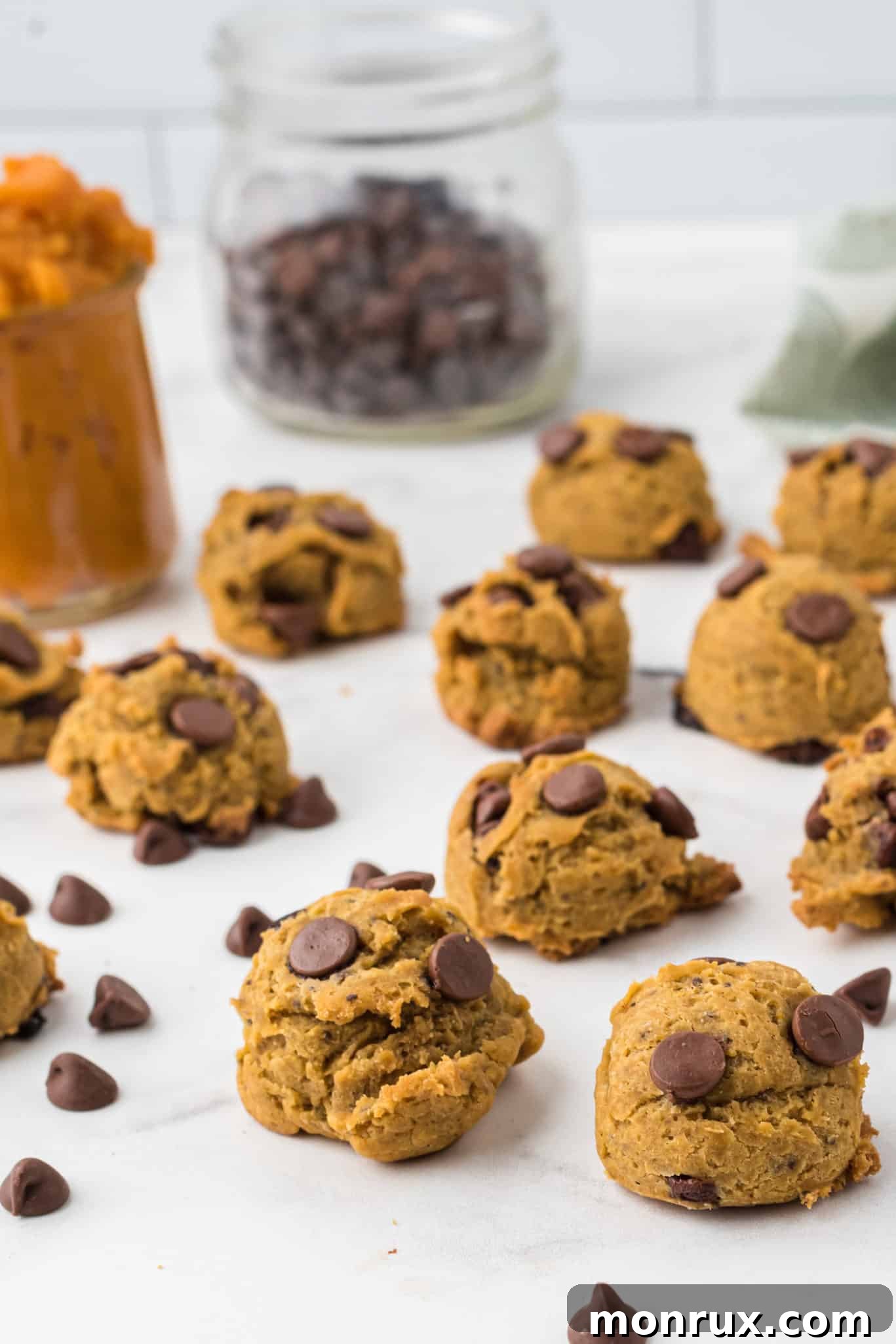 A close-up shot of vegan pumpkin chocolate chip cookies arranged on a pristine countertop, highlighting their inviting texture and generous chocolate chunks.