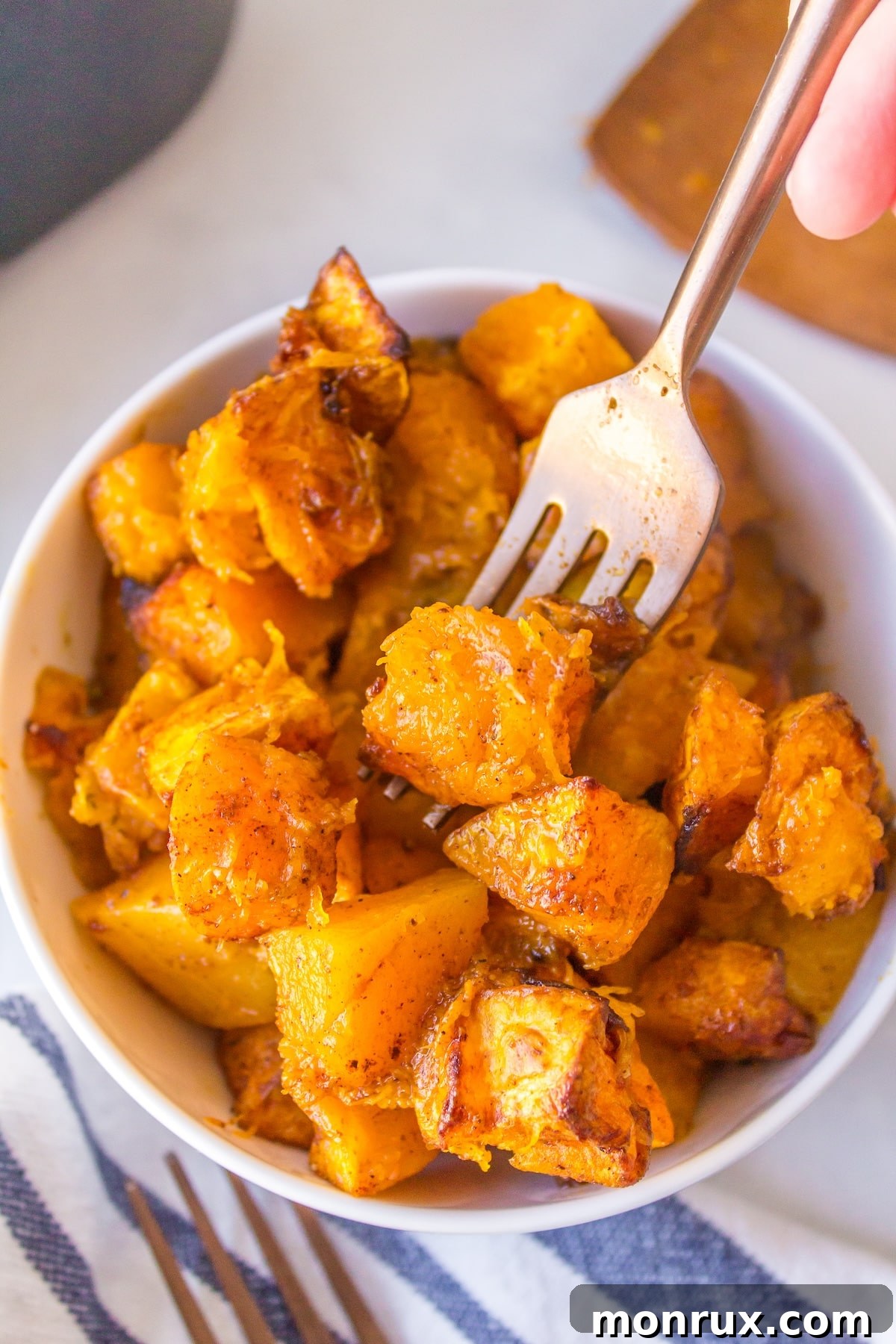 Air fryer butternut squash cubes bite shot with fork, showcasing crispy texture.