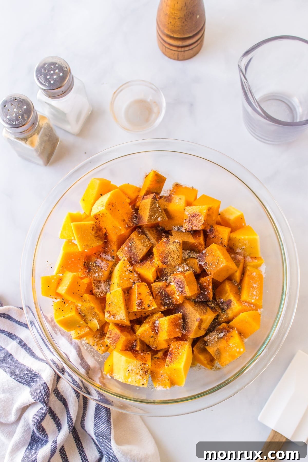 Air fryer butternut squash cubes process shot, showing seasoned squash in a bowl.