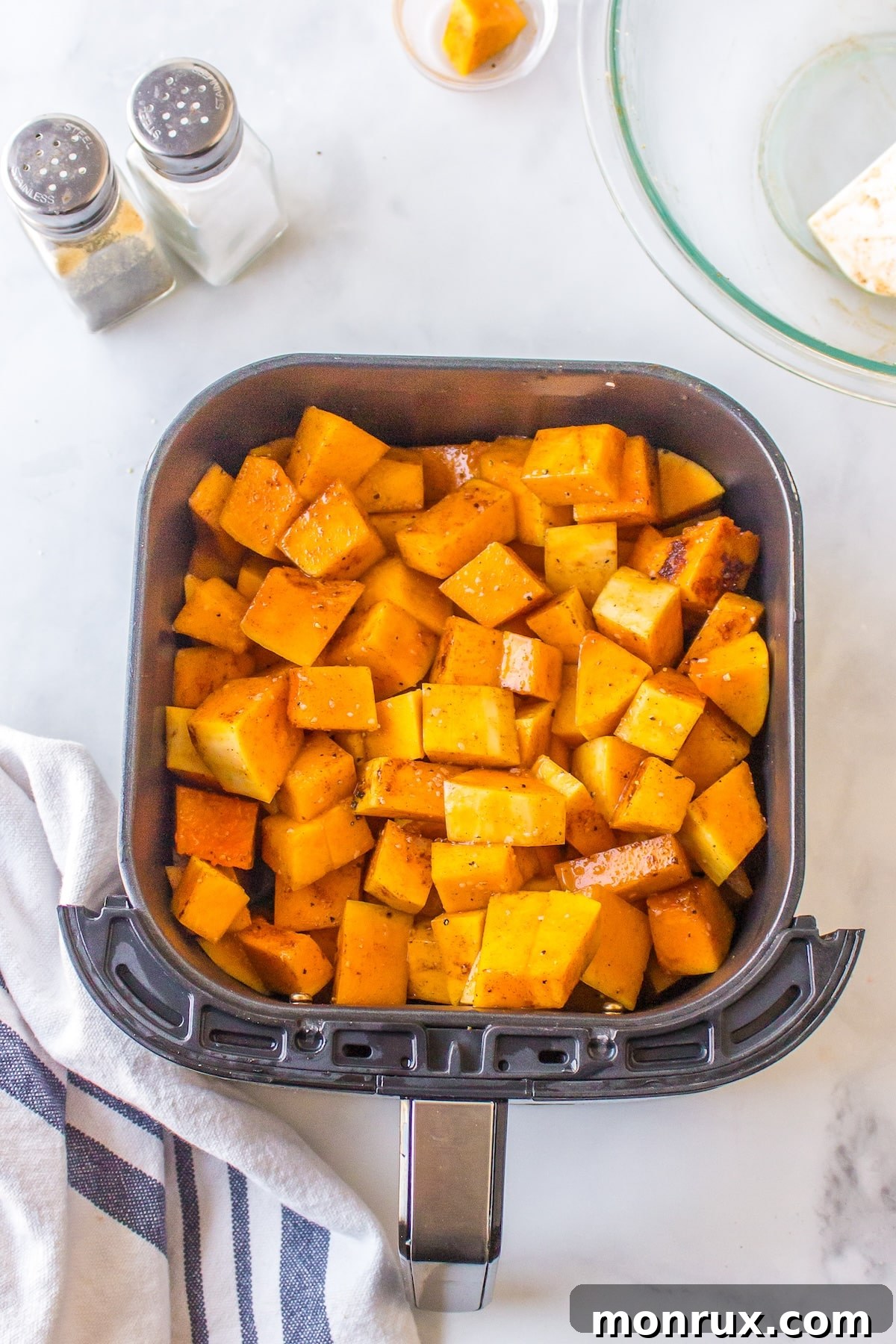 Air fryer butternut squash in basket ready to be baked, in a single layer.