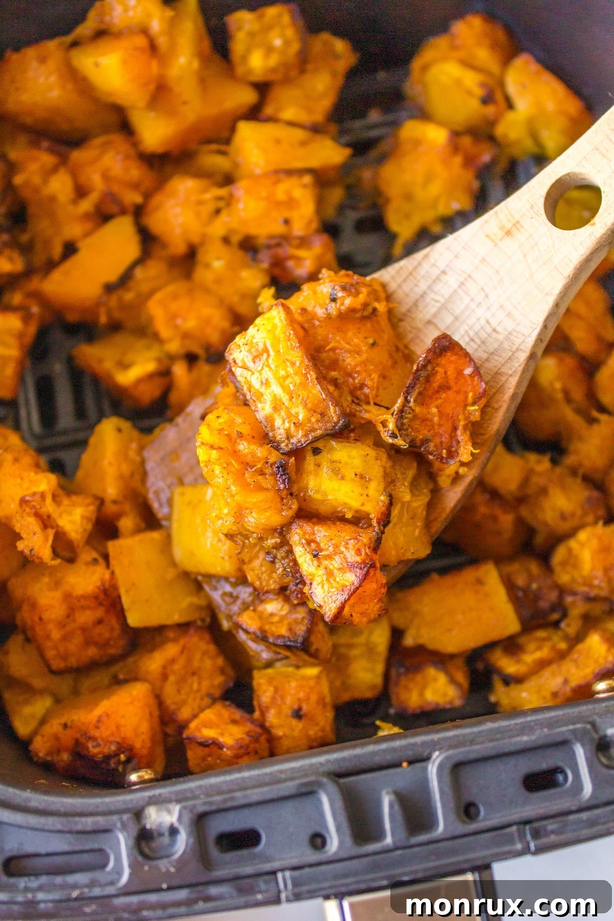 Air fryer butternut squash cubes in basket, freshly cooked and crispy.