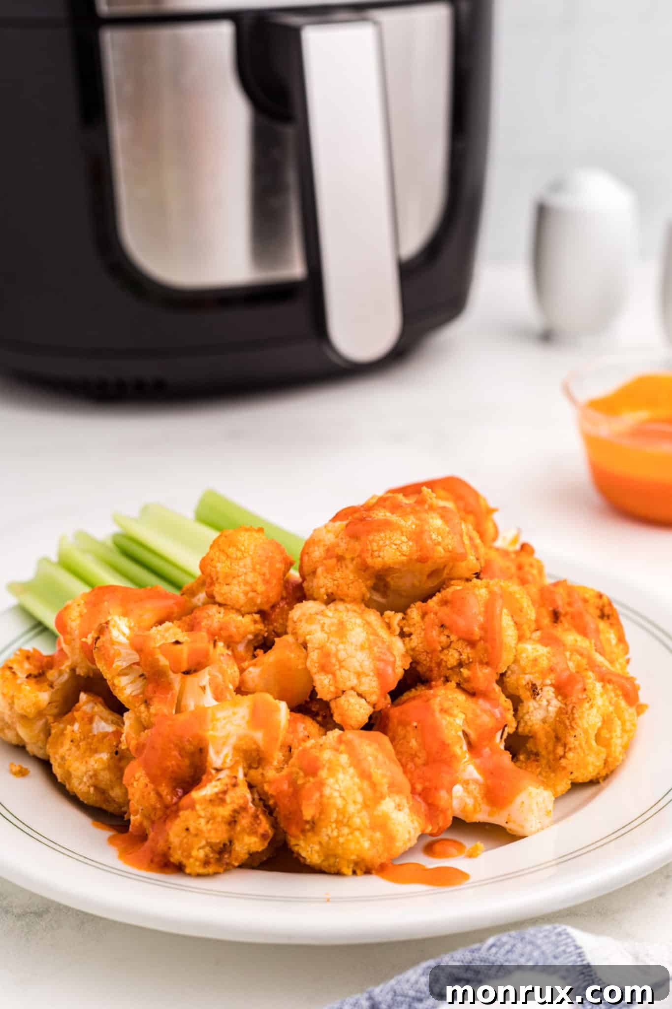 A serving platter of freshly air-fried buffalo cauliflower wings, perfectly sauced and ready to be enjoyed.