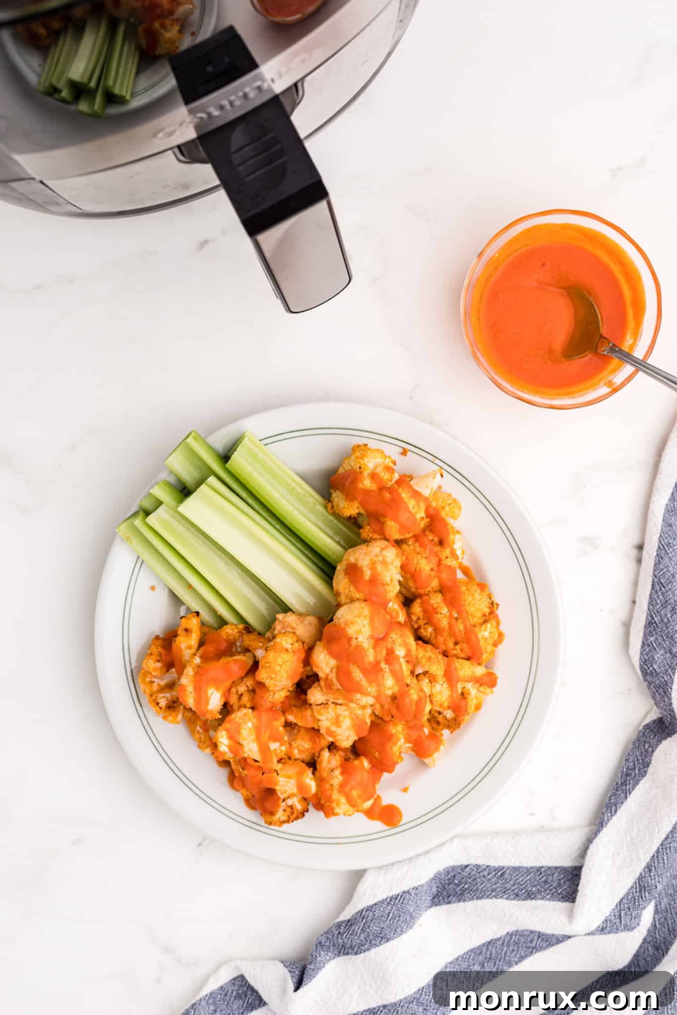 Air fryer buffalo cauliflower served with additional buffalo sauce for dipping, highlighting its rich color and inviting texture.