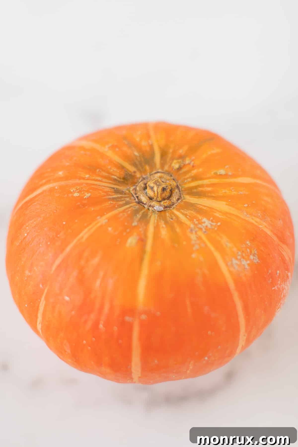 Close-up of a vibrant orange kabocha squash with its distinctive speckled skin, ready for preparation.
