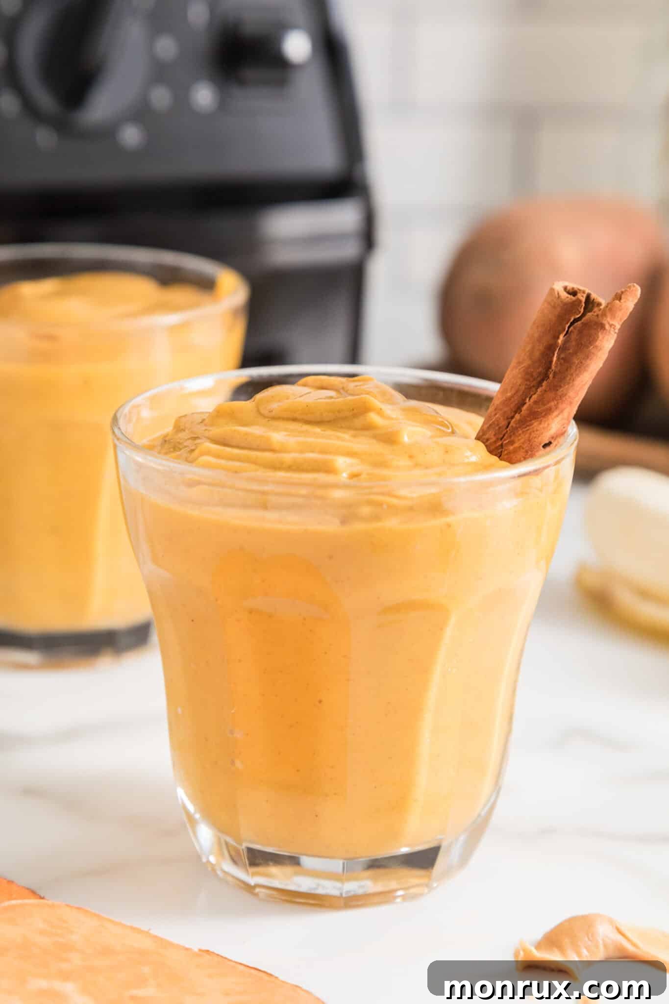 Small glass filled with vegan sweet potato smoothie and a cinnamon stick, illustrating a delicious and healthy breakfast or snack.