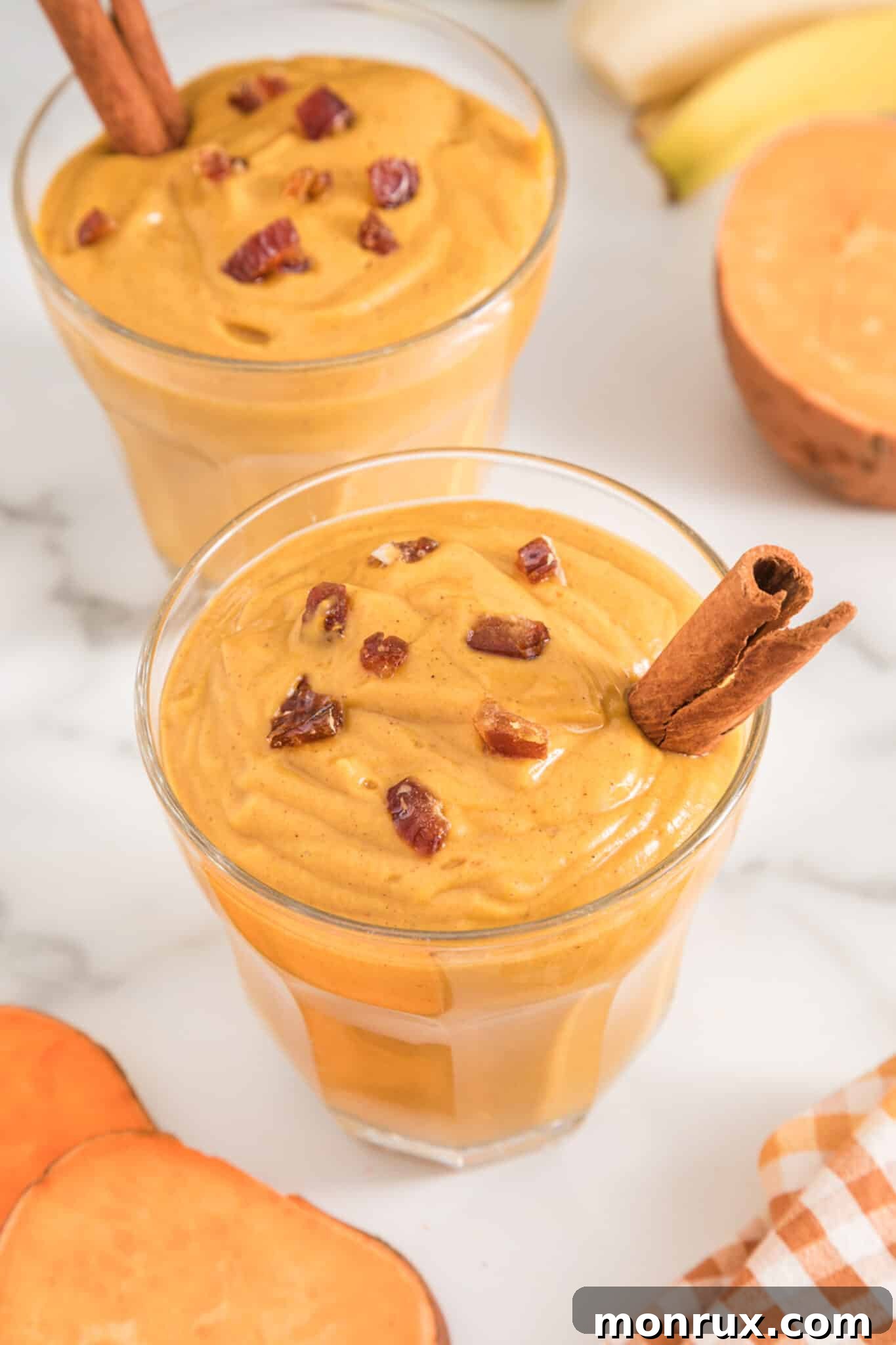 Two short glasses of vegan sweet potato smoothie, garnished with a cinnamon stick, ready to be enjoyed.