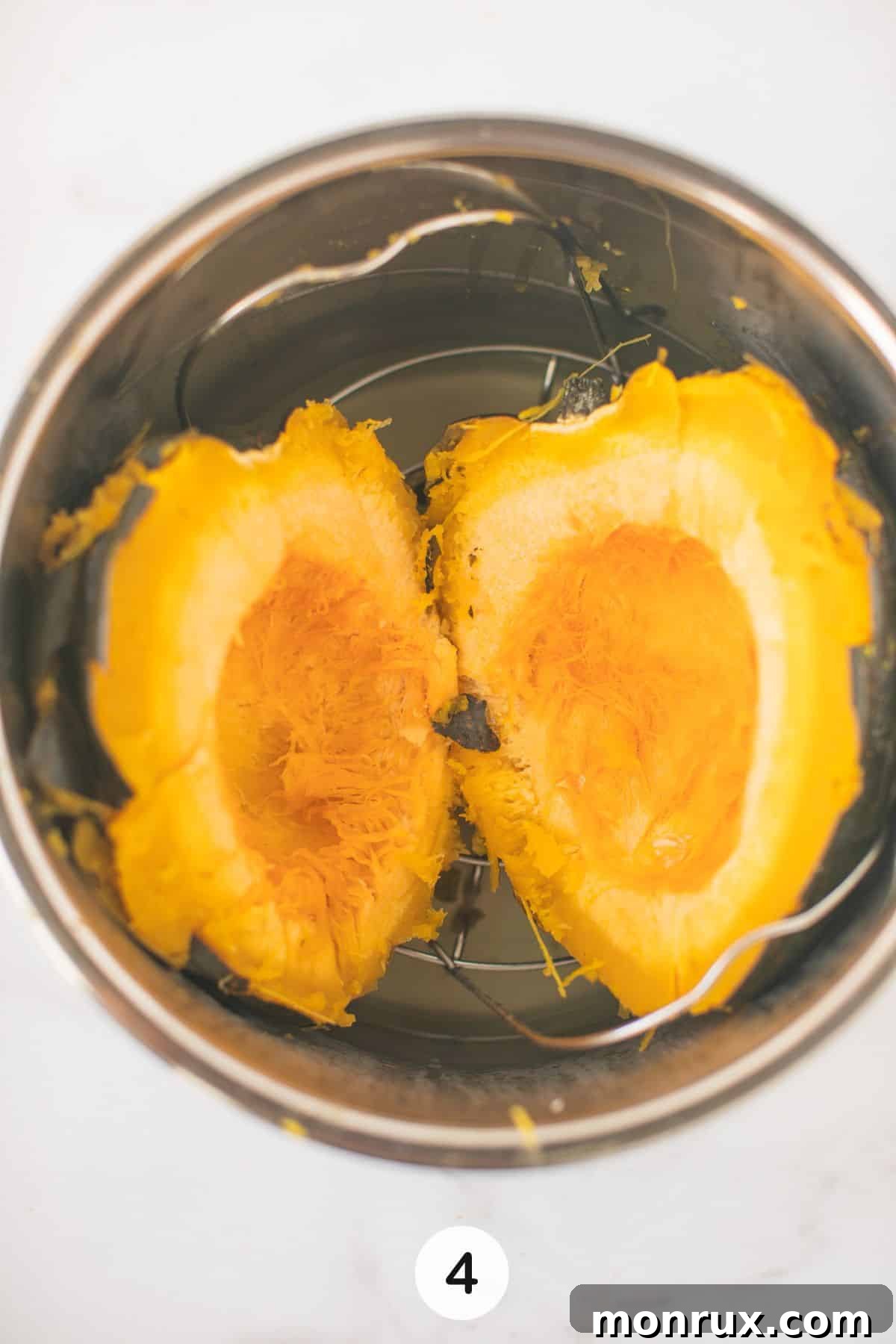 Two halves of cooked acorn squash being placed back into the Instant Pot for a second round of cooking.