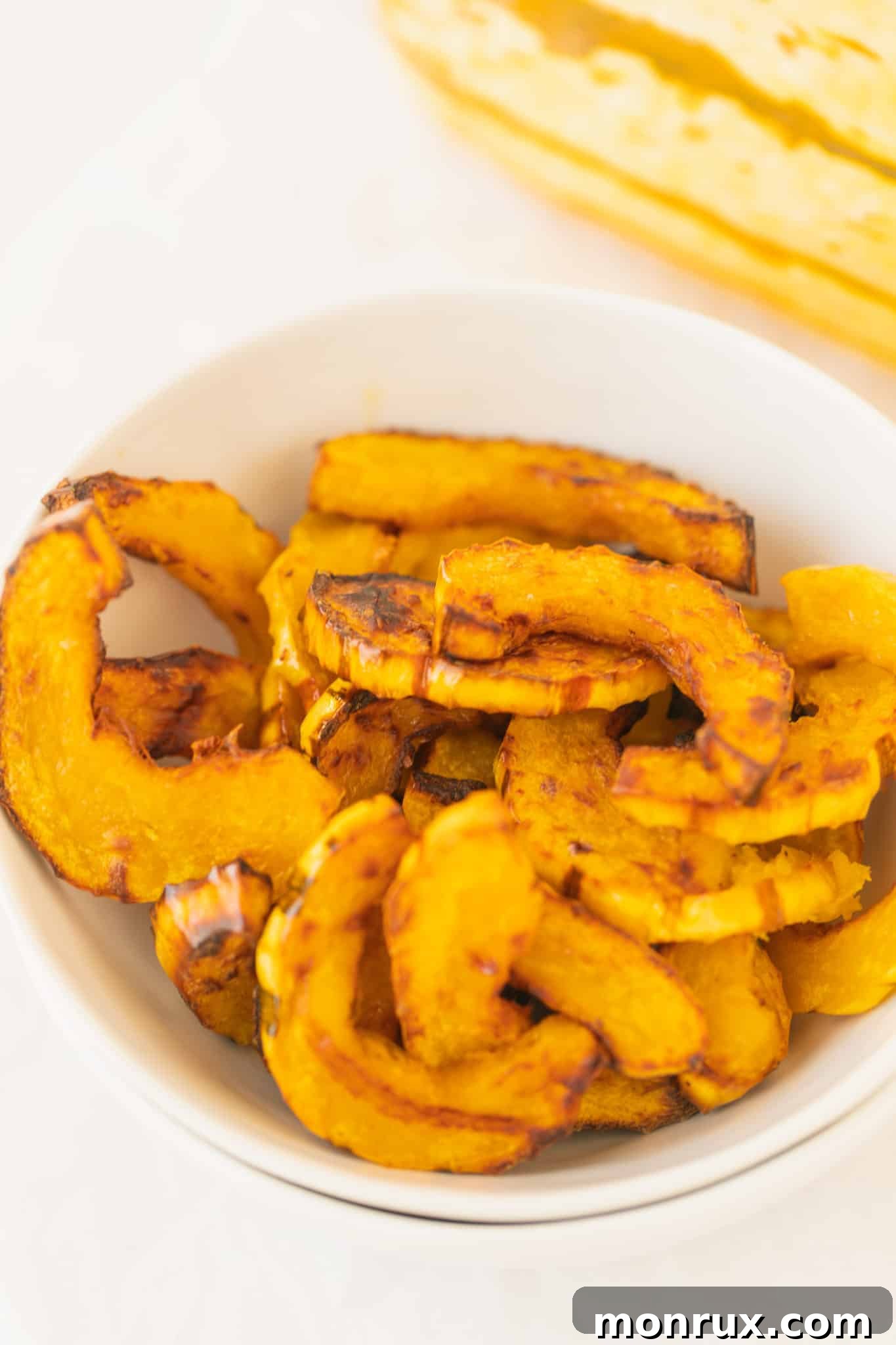 A bowl of beautifully roasted delicata squash, garnished and ready to be savored as a wholesome side dish.