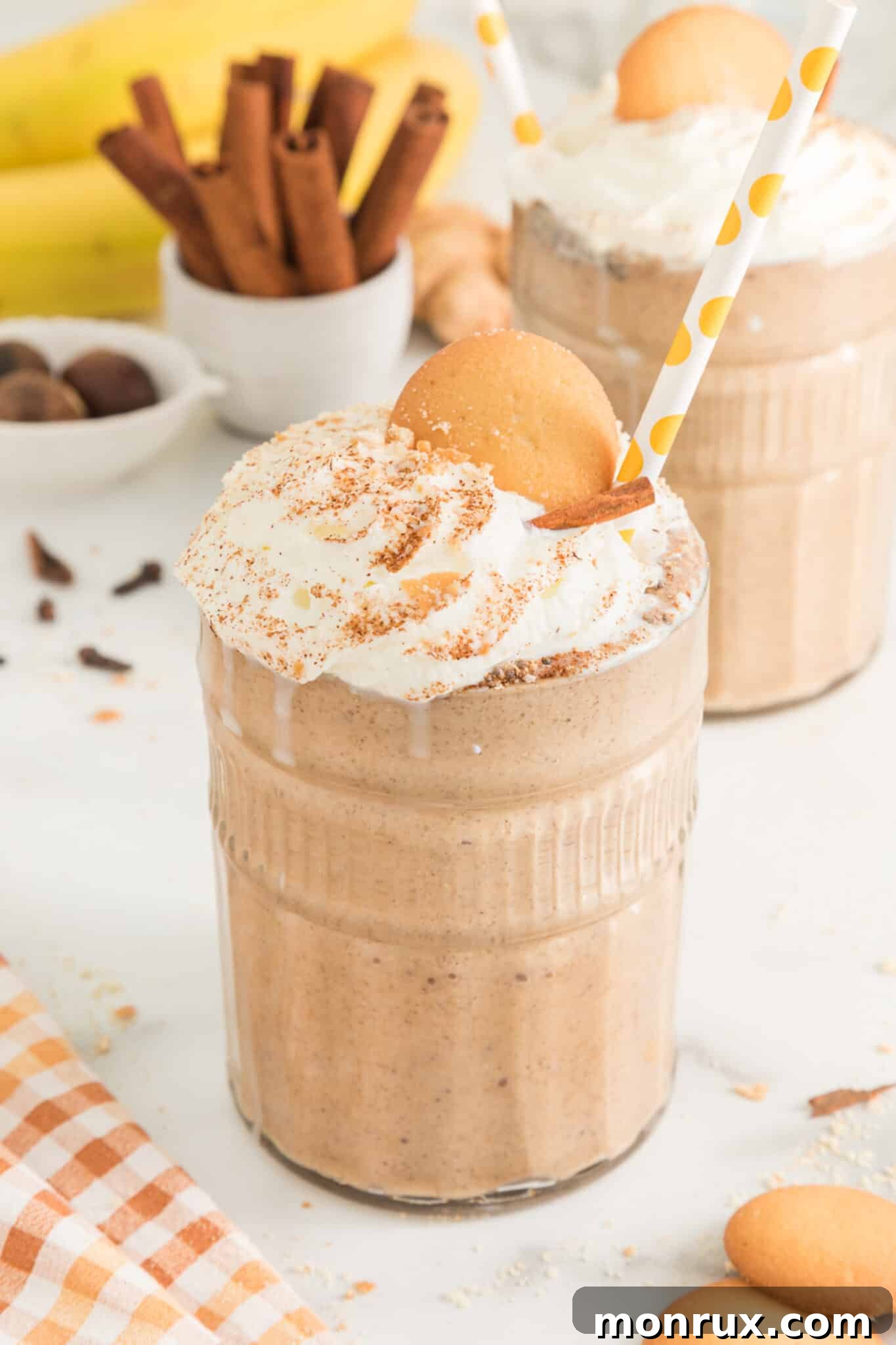 Two glasses of gingerbread smoothie topped with whipped cream and cookies, garnished for a festive look.