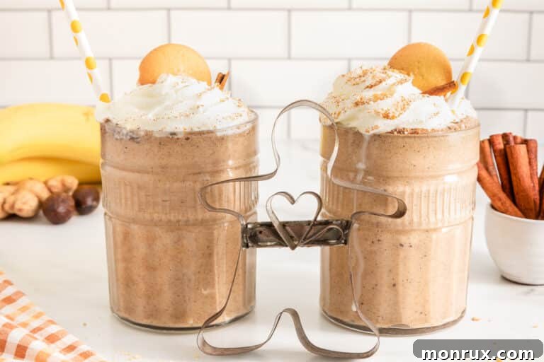 Two glasses of gingerbread smoothie topped with whipped cream and cookies, perfect for a festive occasion.