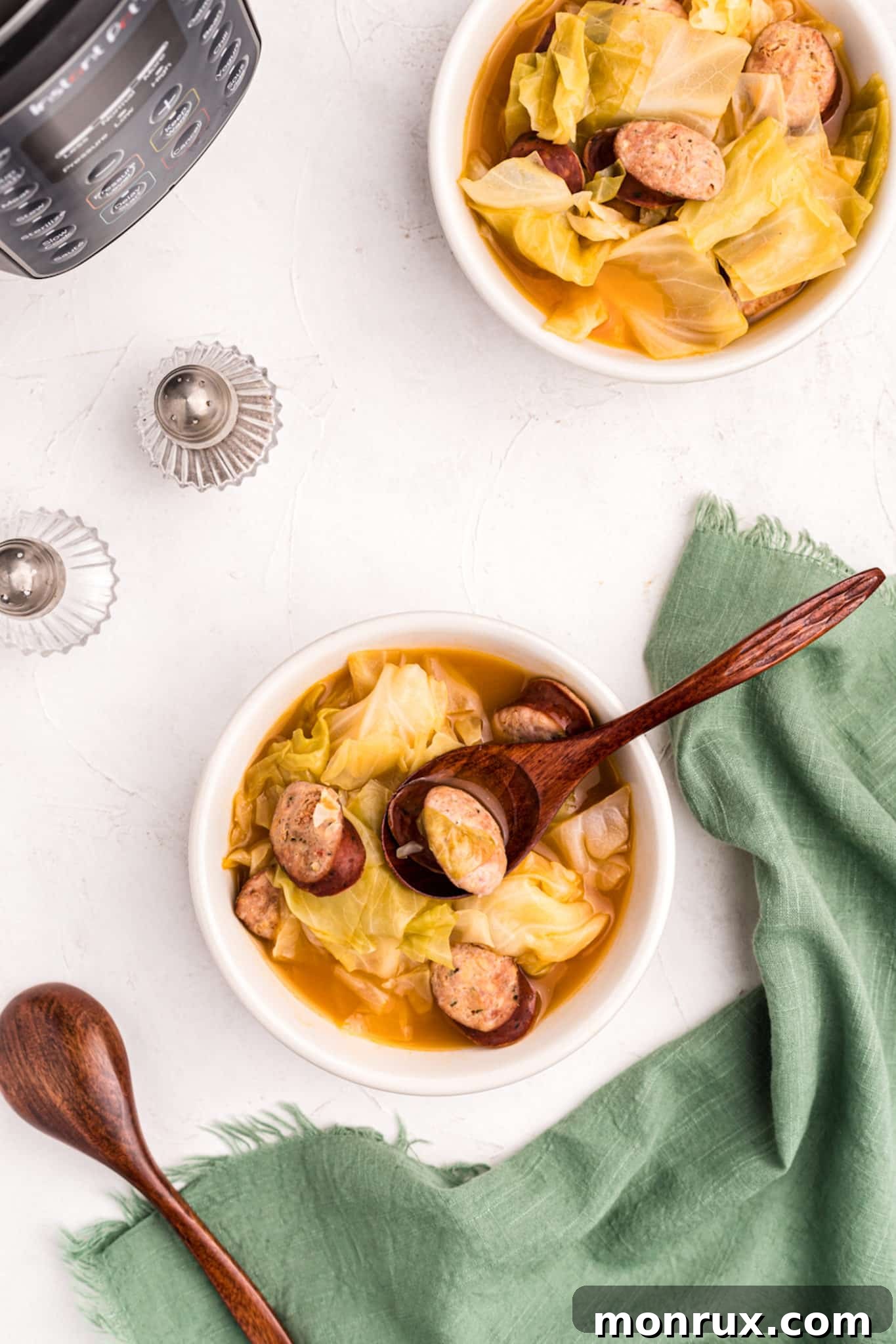 instant pot pressure cooker cabbage and sausage soup served in white bowls.