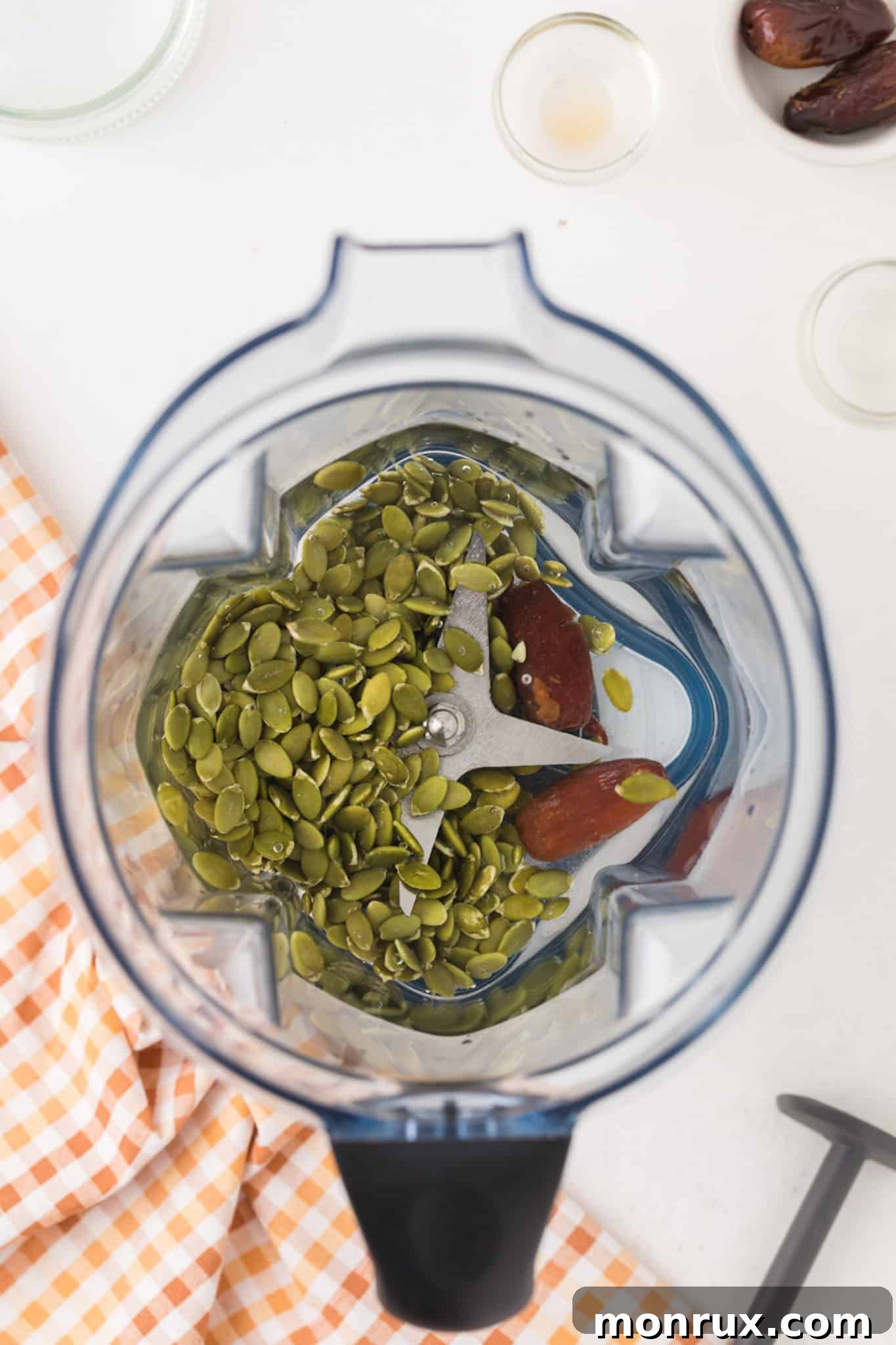 Raw ingredients for pumpkin seed milk, including seeds, water, and dates, inside a Vitamix blender pitcher.