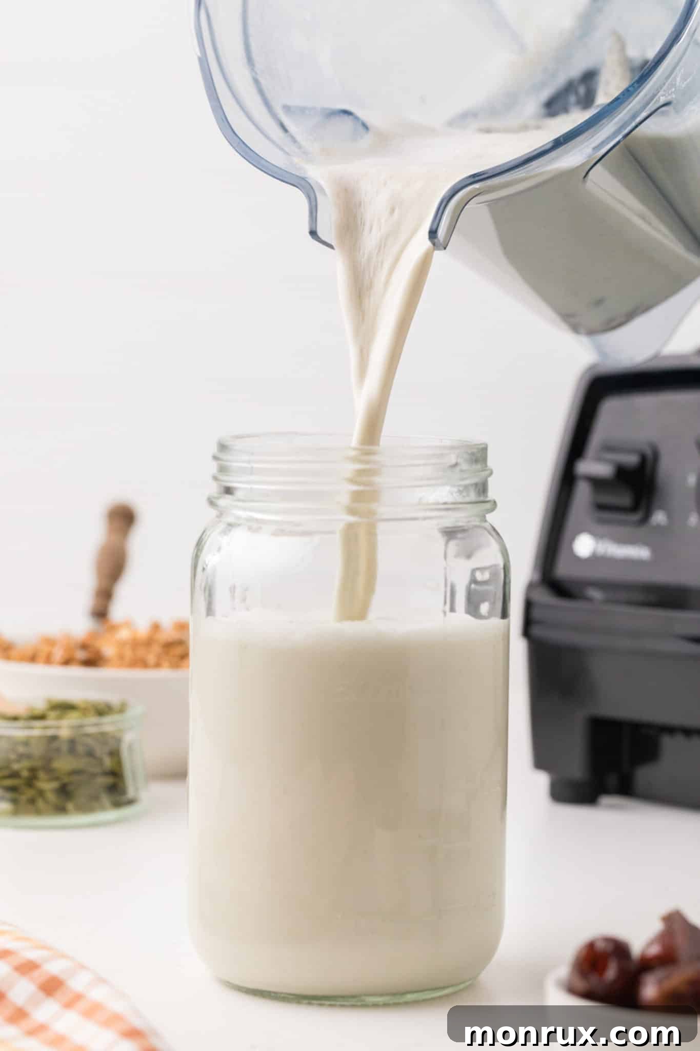 Pouring freshly made pumpkin seed milk into a glass jar for storage.