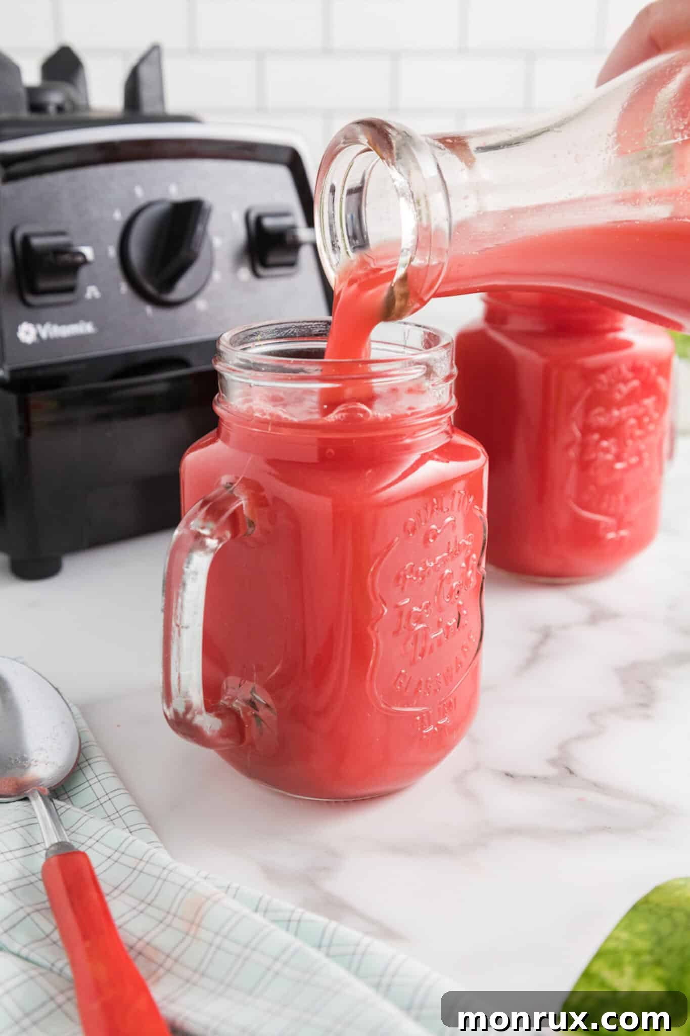 Freshly made watermelon mint juice being poured into a elegant glass, ready to be served.