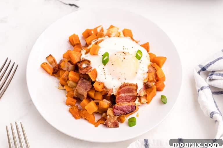 A delicious serving of Sweet Potato Apple Hash, elegantly plated and topped with a perfectly cooked fried egg and a sprinkle of fresh herbs, ready for a healthy meal.