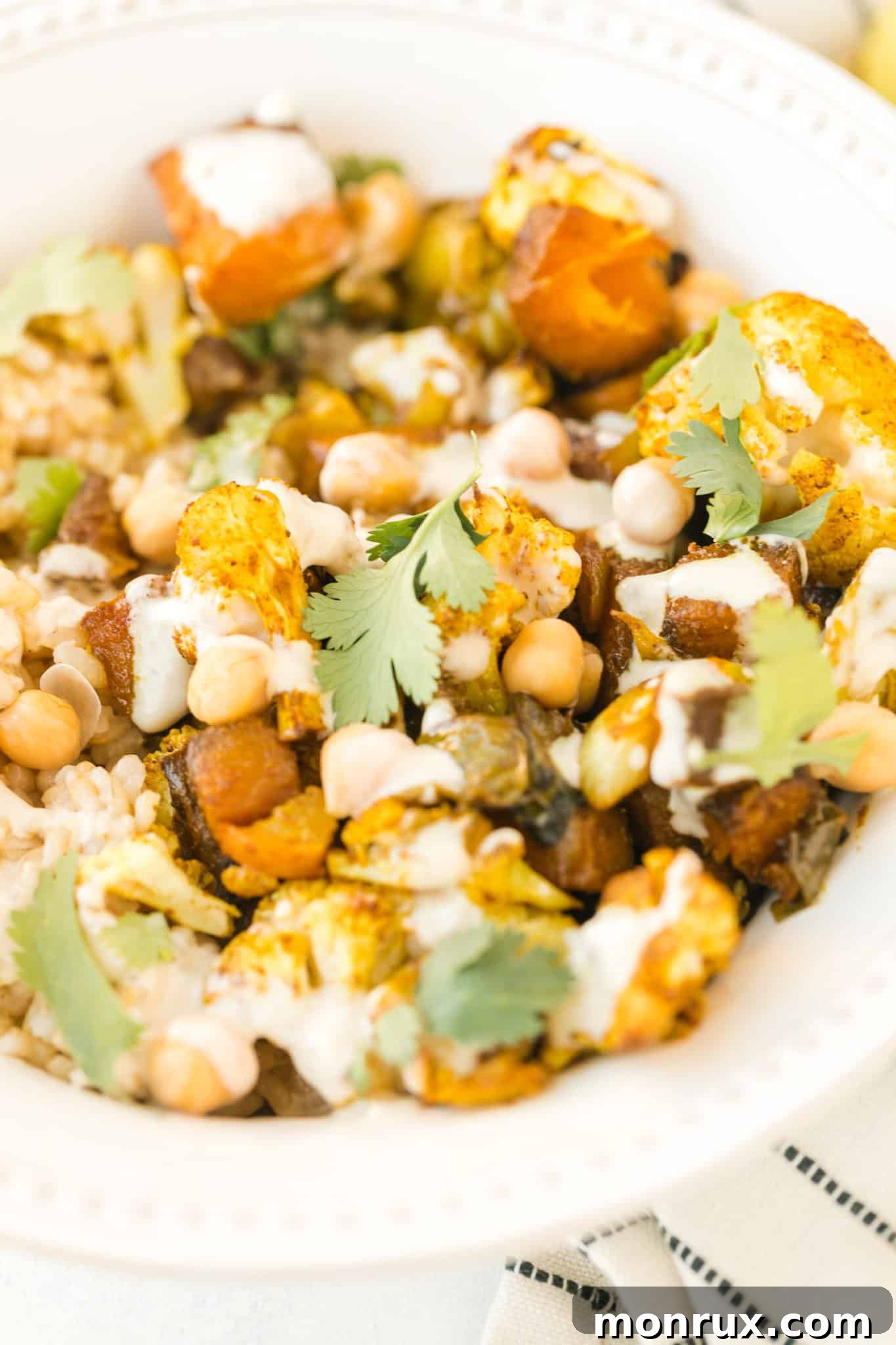 A beautifully assembled anti-inflammatory veggie bowl, rich with roasted vegetables and chickpeas, topped with a creamy tahini drizzle, presented in a rustic bowl.