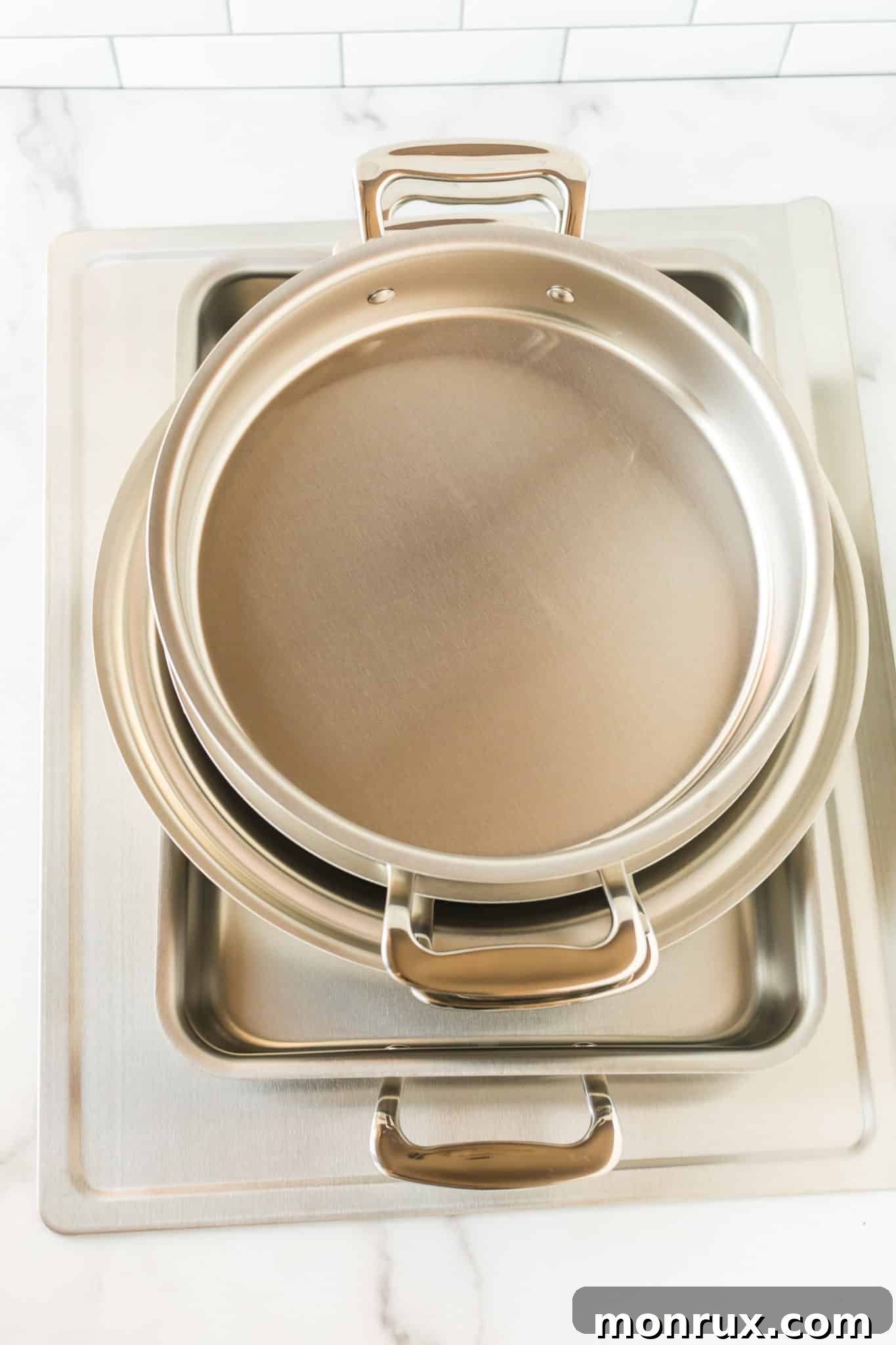 A pristine stainless steel bakeware set by 360 Cookware elegantly arranged on a kitchen countertop, ready for use.