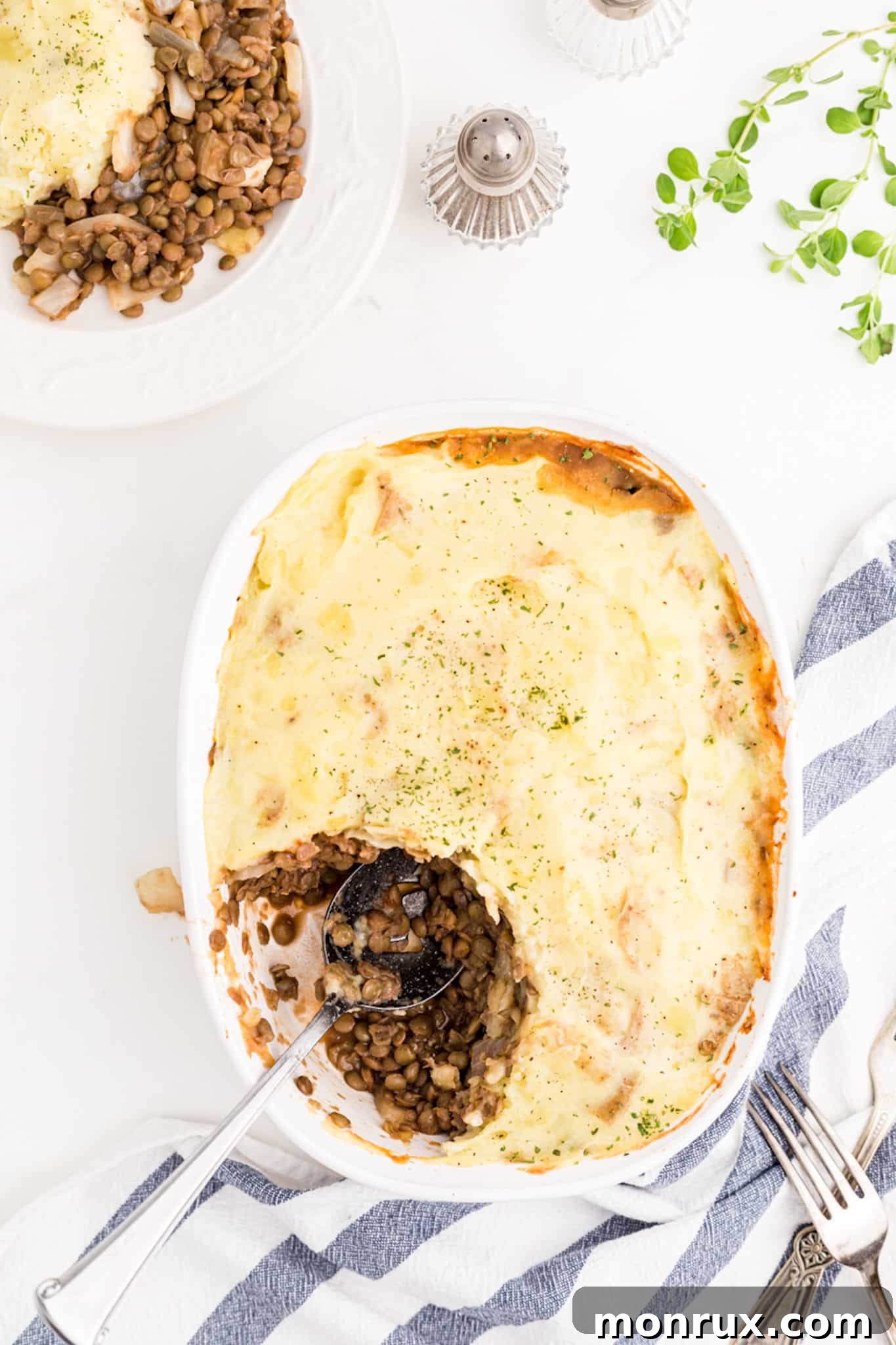 A perfectly baked and golden-brown vegan lentil shepherd's pie resting on a rustic tabletop, inviting you to dig in.
