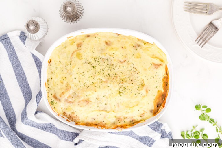 A delicious vegan lentil shepherd's pie beautifully presented on a wooden table, with steam rising.