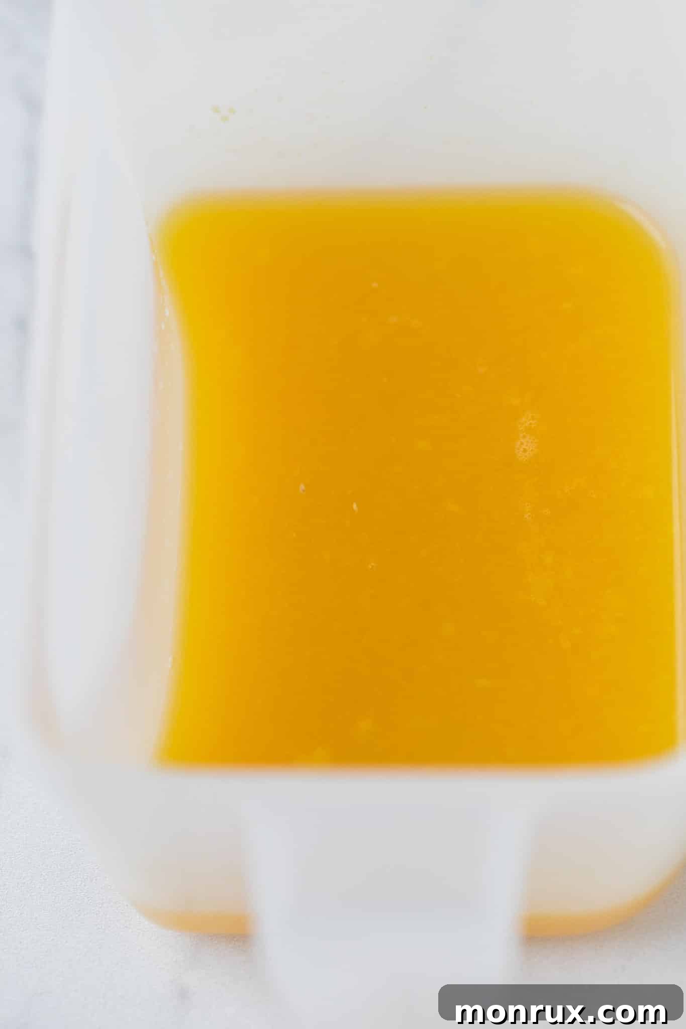 A bright, golden-yellow ginger juice captured in a glass, freshly juiced and ready for the next step.
