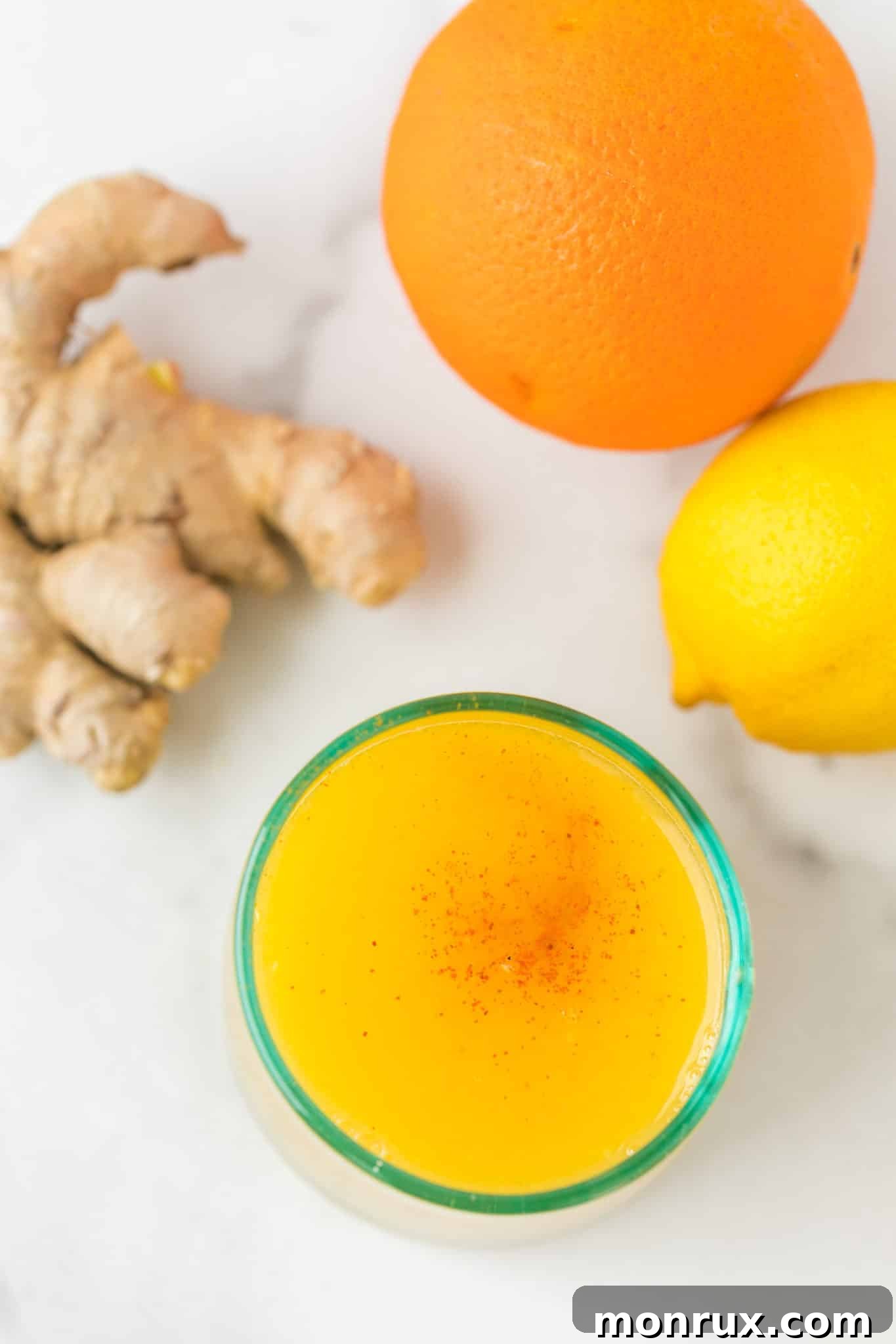 A close-up of a refreshing glass of lemon ginger juice, garnished with a light dusting of cayenne pepper on top, ready to be enjoyed.