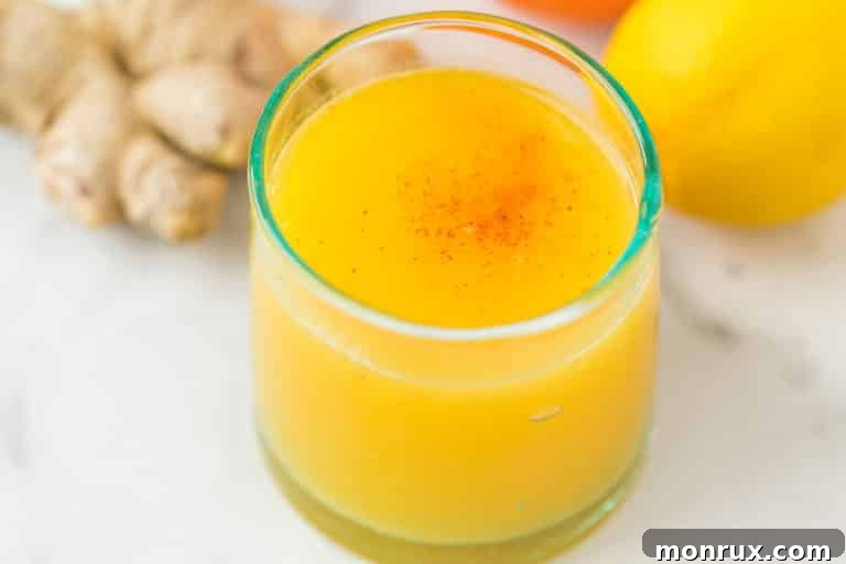 Glass of vibrant ginger citrus immune boosting shot, perfectly garnished