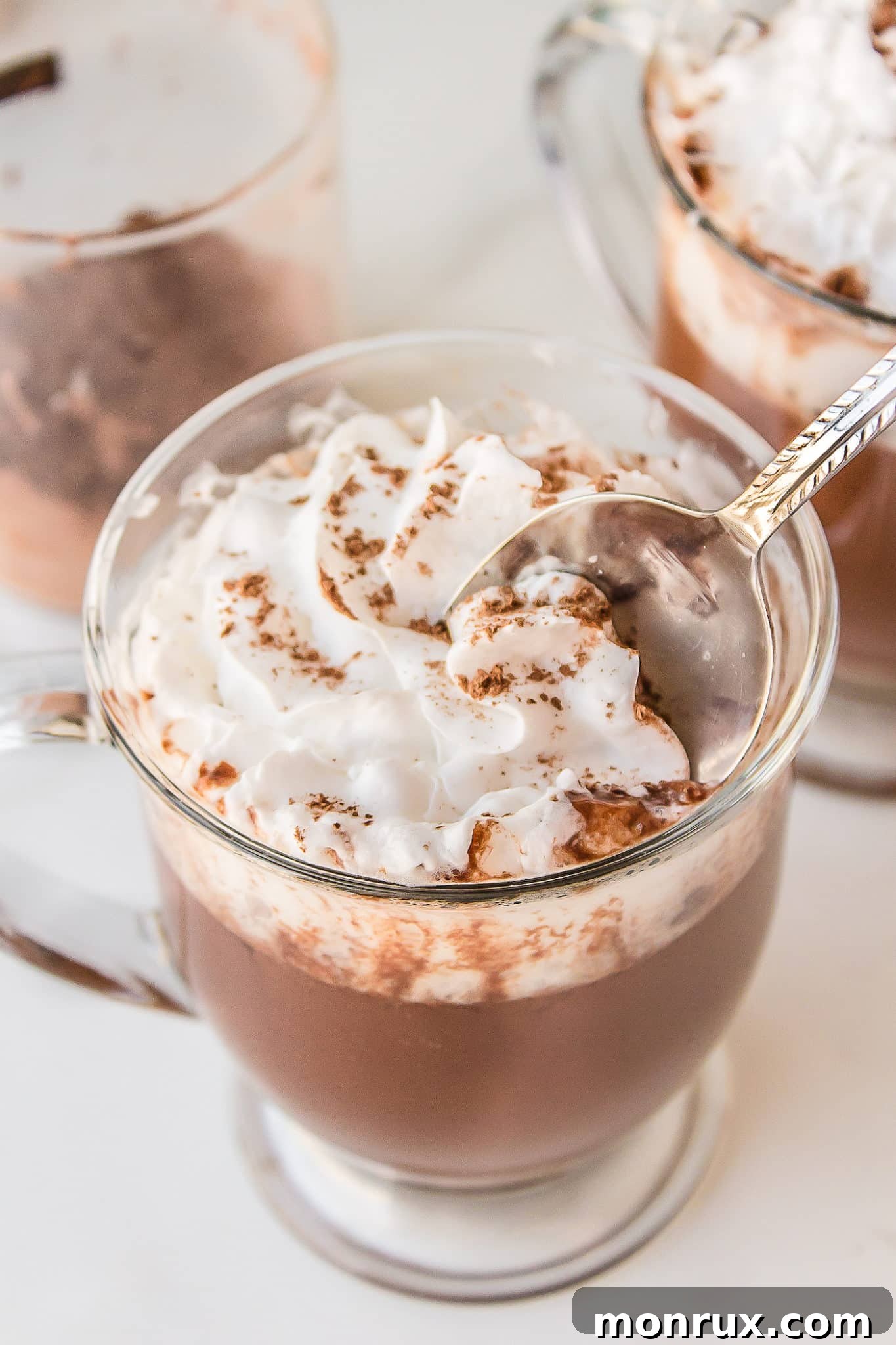 A cozy mug of healthy hot chocolate, topped generously with a spoonful of fluffy coconut whipped cream, looking utterly irresistible.