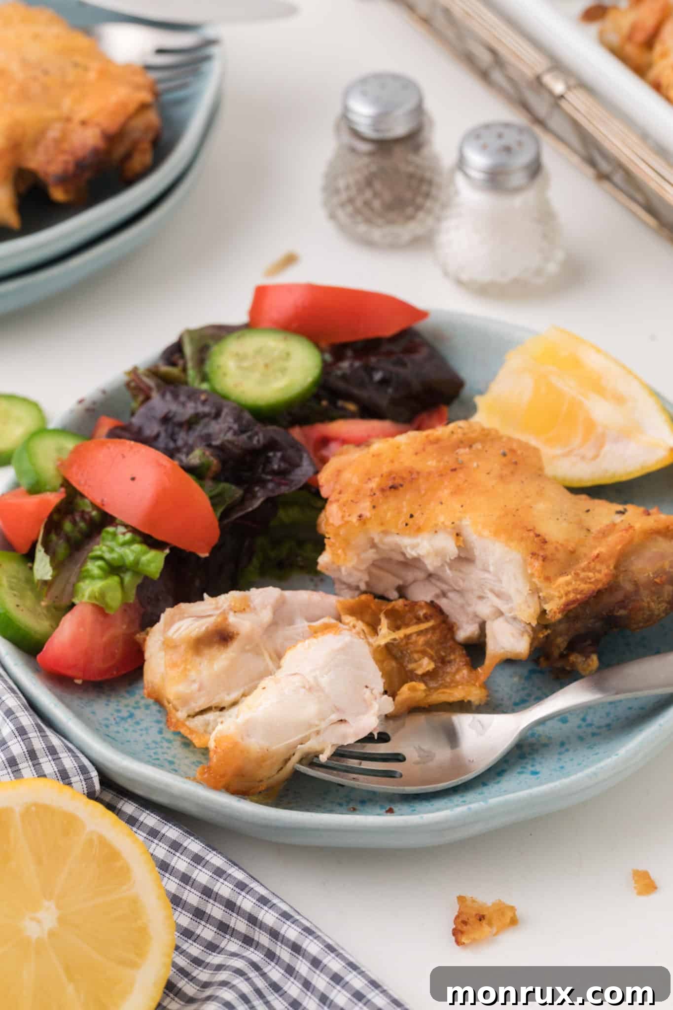 Air fried bone-in chicken thighs served on a plate, garnished with fresh herbs and lemon wedges.