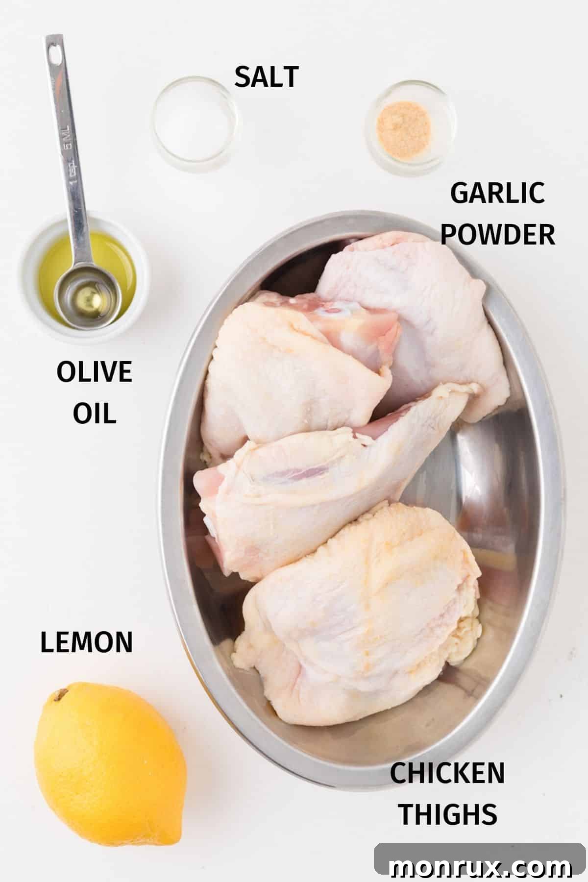 Ingredients for air fryer bone-in chicken thighs laid out: chicken thighs, olive oil, garlic powder, salt, and fresh lemons.