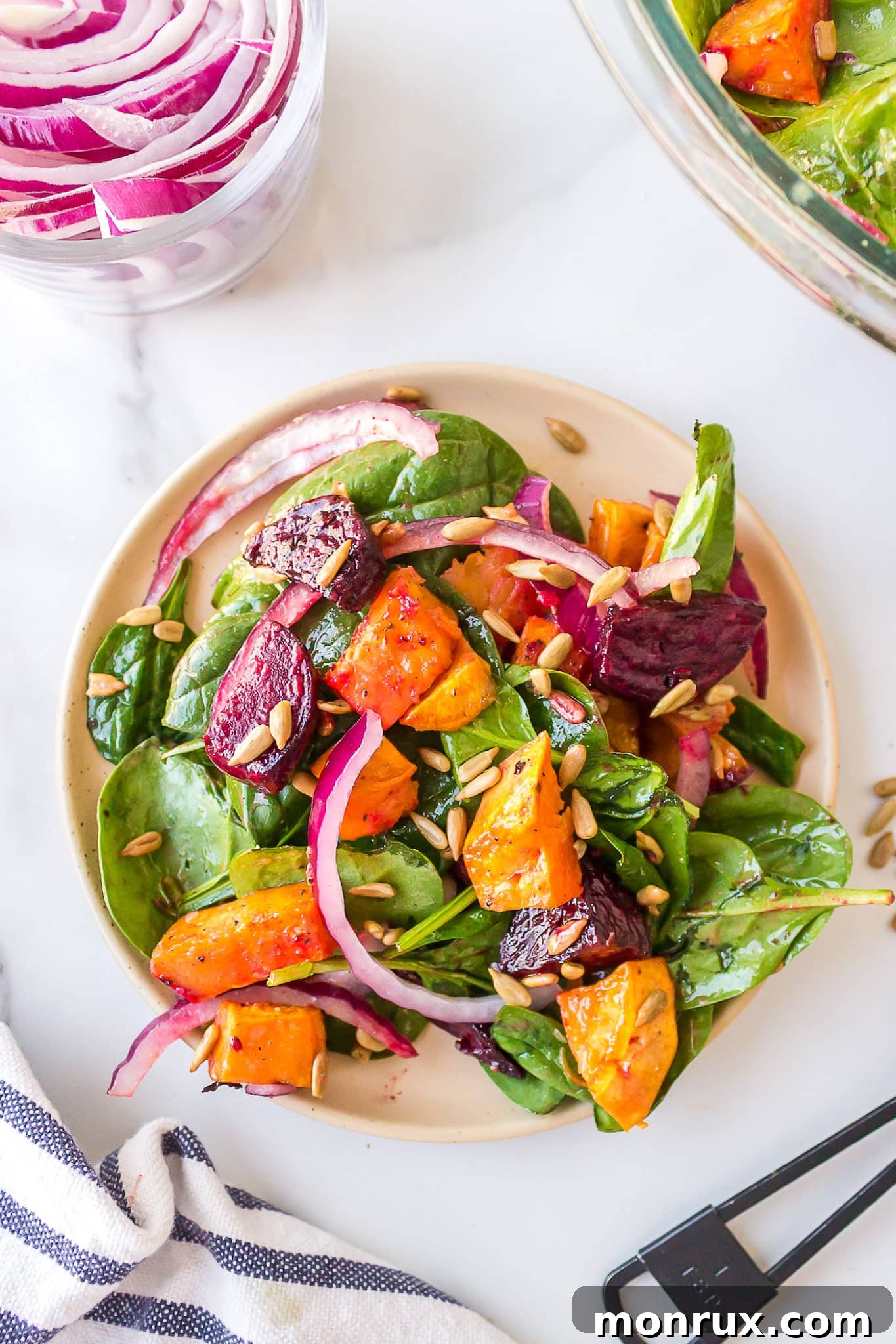 Vibrant roasted sweet potato and beet salad with fresh spinach on a dinner plate, ready to be enjoyed.