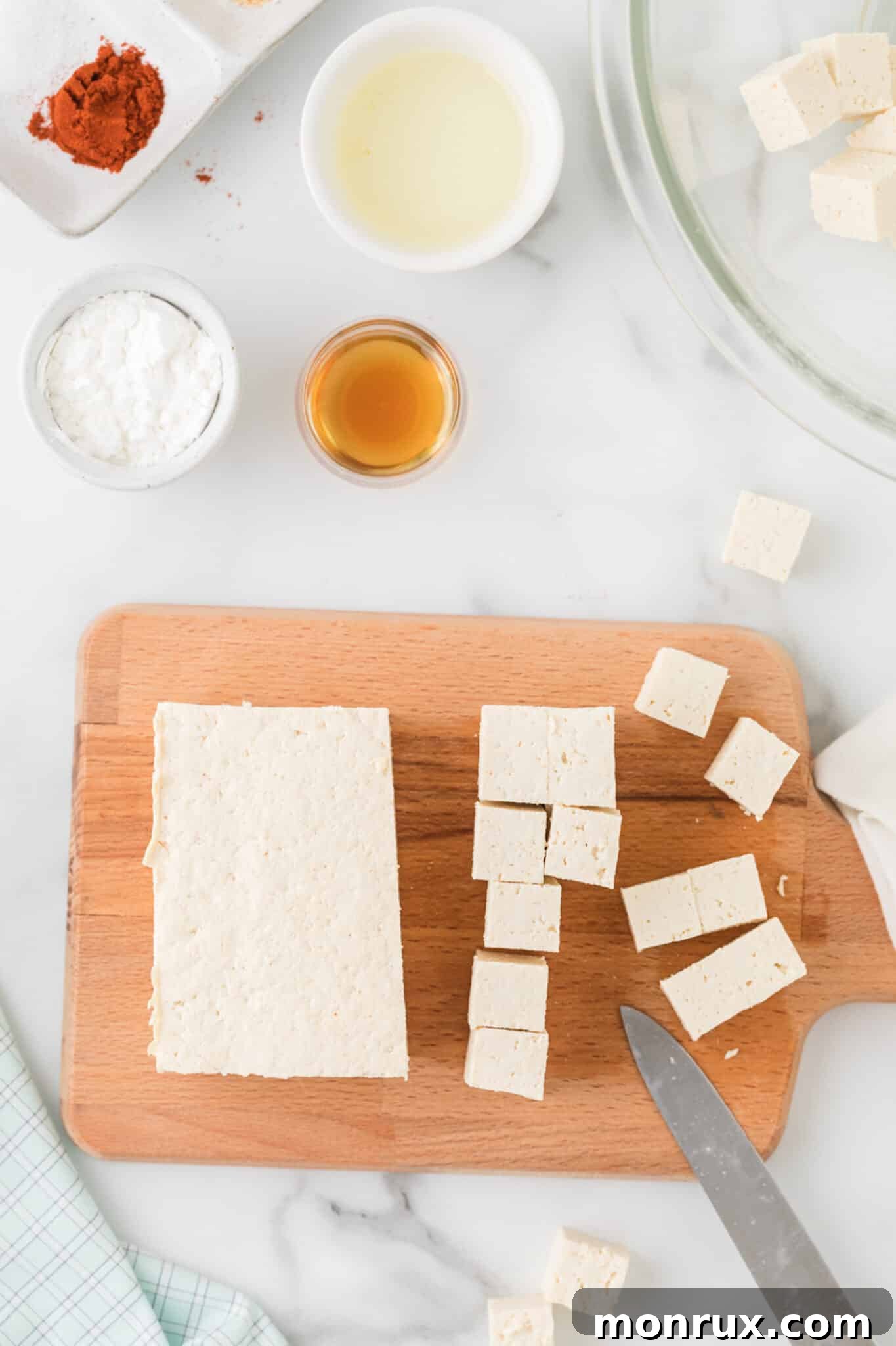 Freshly chopped extra-firm tofu pieces on a cutting board, ready for seasoning.