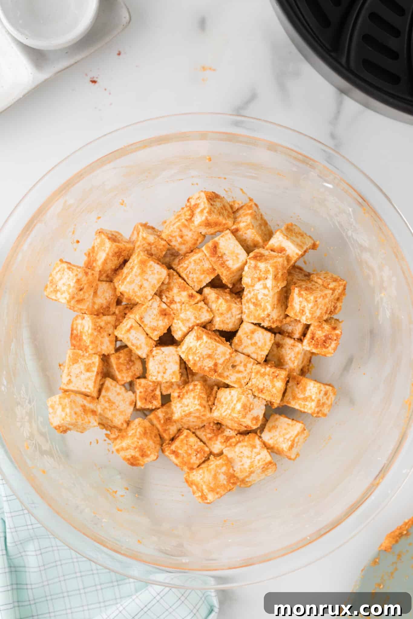Seasoned and cubed tofu in a mixing bowl, fully coated and ready for the air fryer.