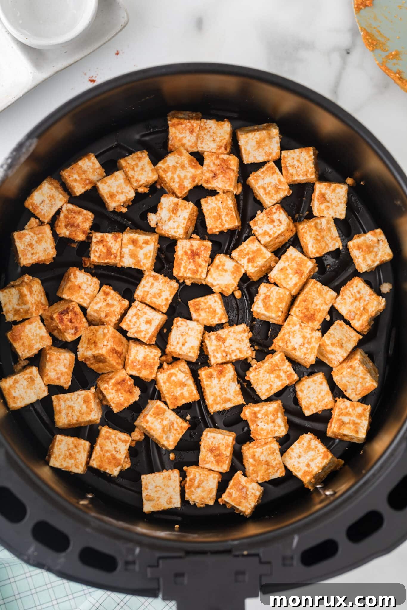 Crispy golden tofu pieces perfectly air-fried in an air fryer basket, ready to be served.
