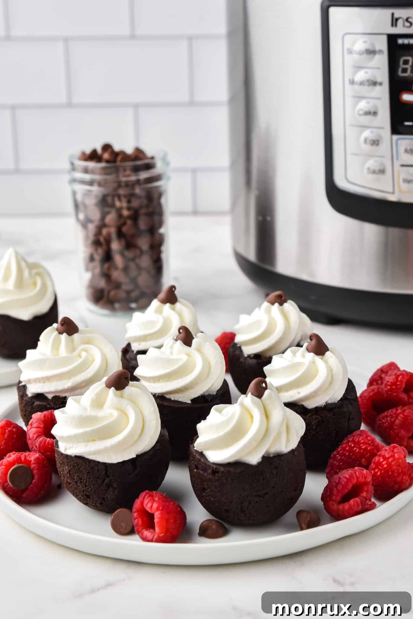 Instant Pot brownie bites with a dollop of whipped cream on a white plate, highlighting their rich chocolatey appeal.