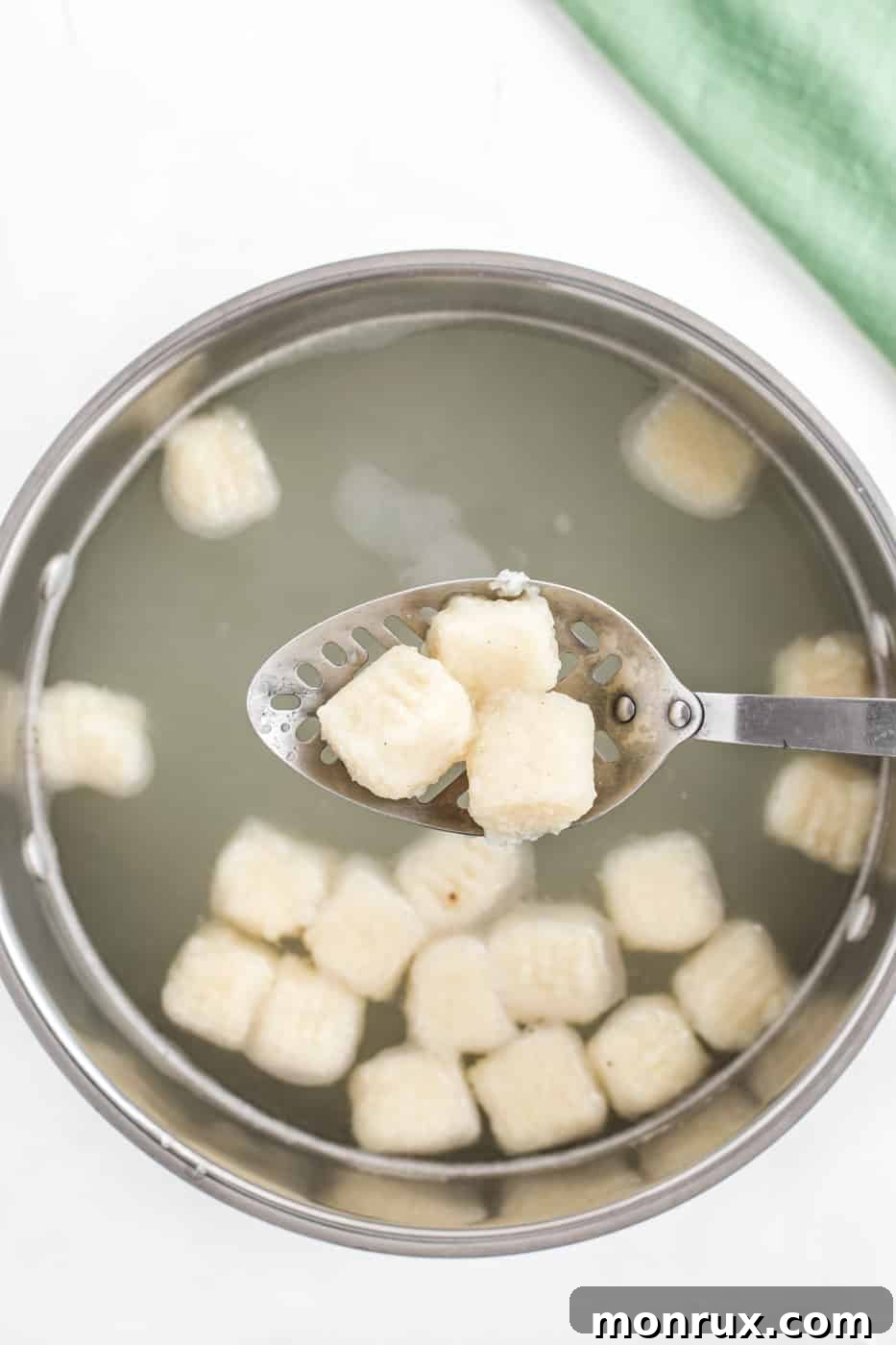 Gluten-free gnocchi boiling in a pot of water, floating to the surface as they cook, ready to be removed.