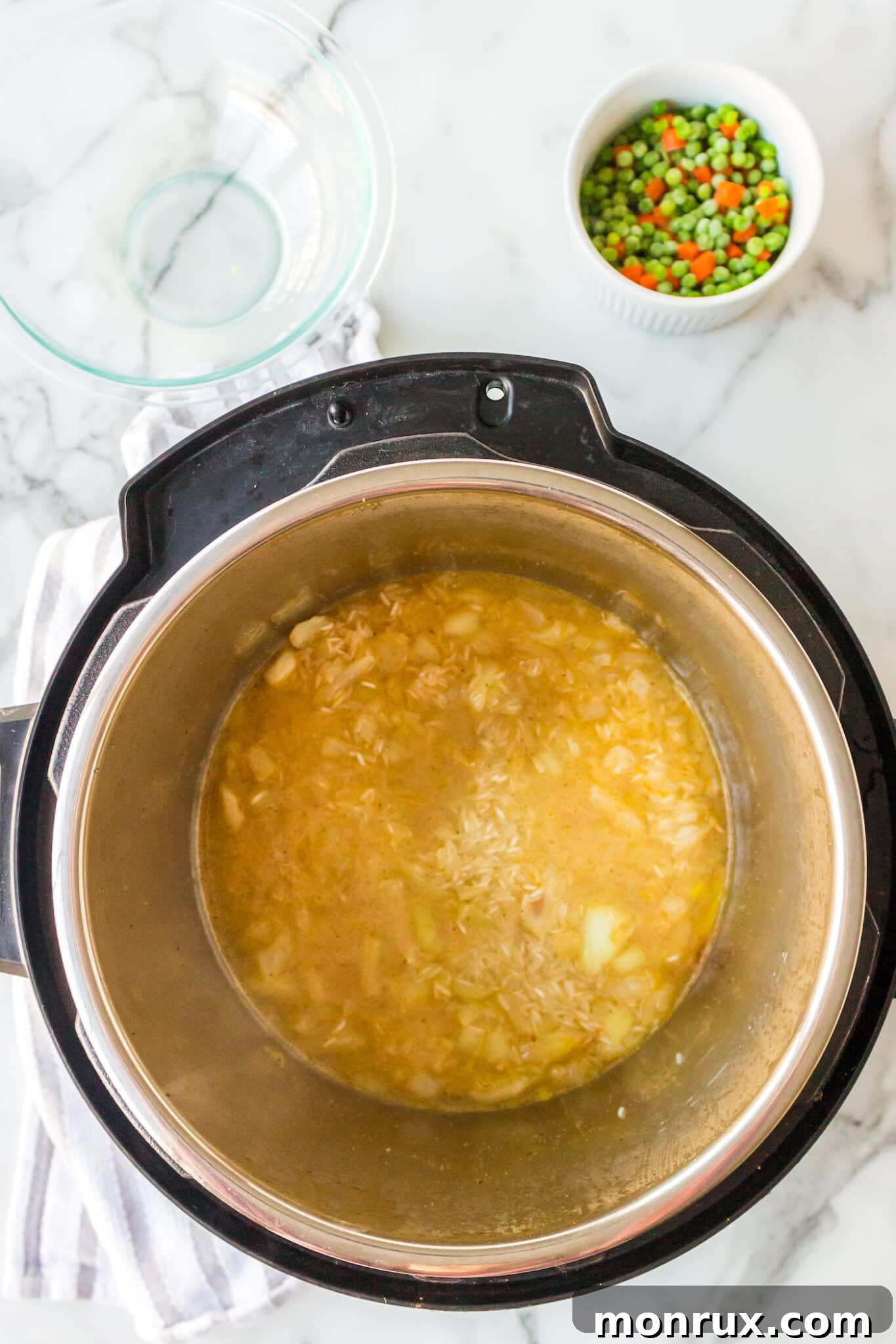 rice and broth inside instant pot with onions.