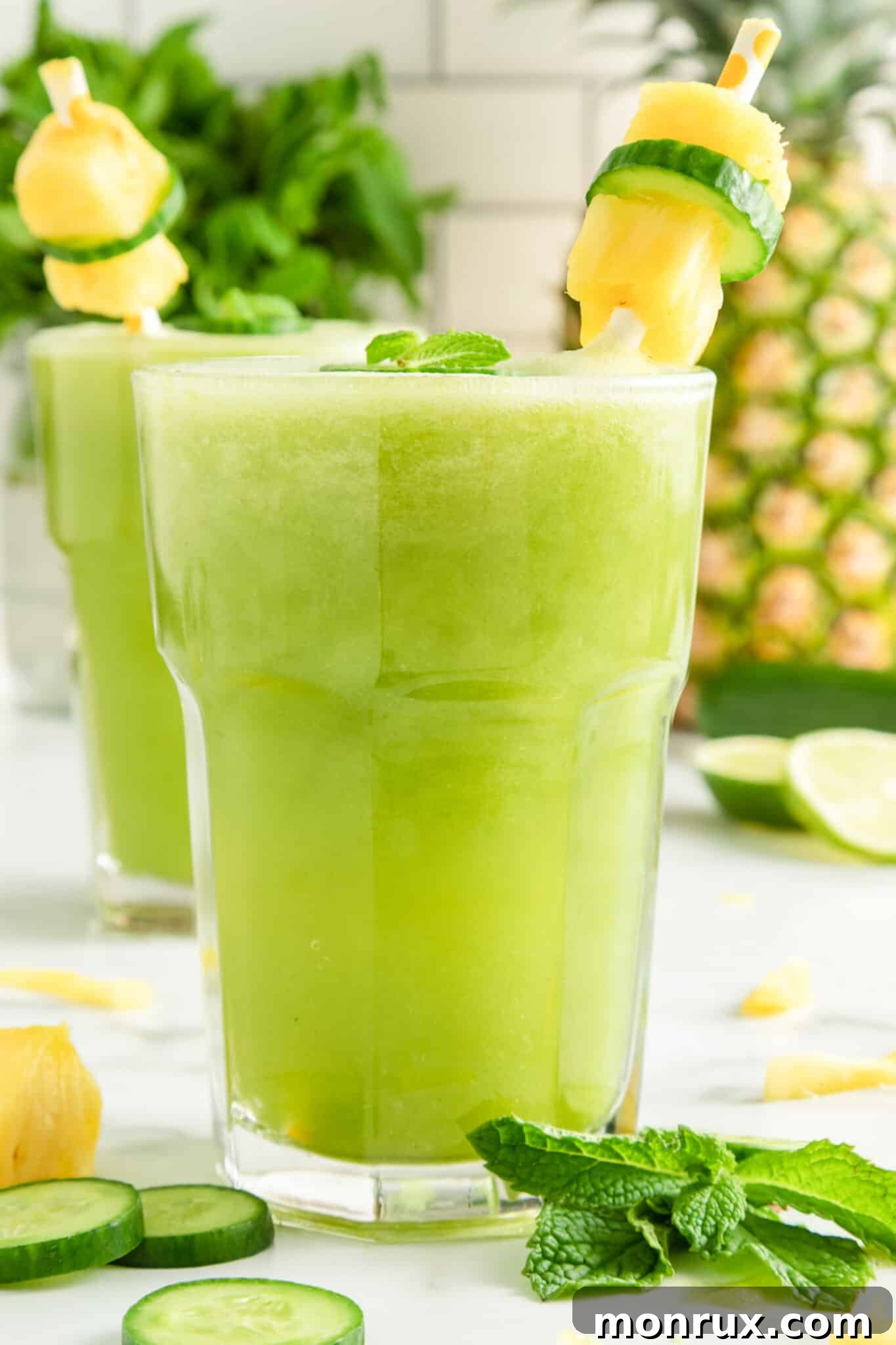 A close-up, side view of the refreshing cucumber pineapple smoothie in a glass, showcasing its vibrant green hue.