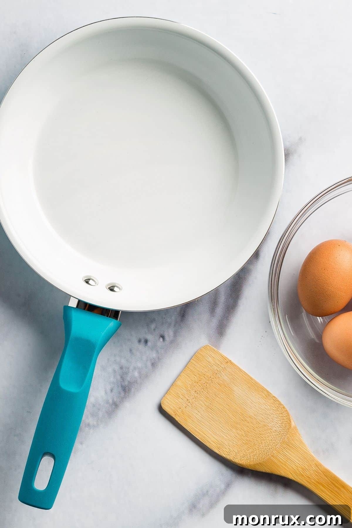 A vibrant ceramic skillet sits on a sleek kitchen countertop, gleaming under soft light, ready to transform fresh eggs into a delicious meal. Its smooth, non-stick surface promises effortless cooking and easy cleanup, a testament to modern kitchen innovation.