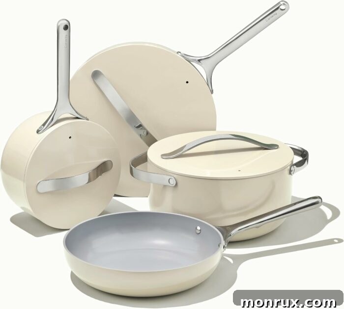 A stylish Caraway ceramic cookware set in a soft cream color, neatly arranged with a matching lid holder, showcasing its elegant design and practical storage solutions.