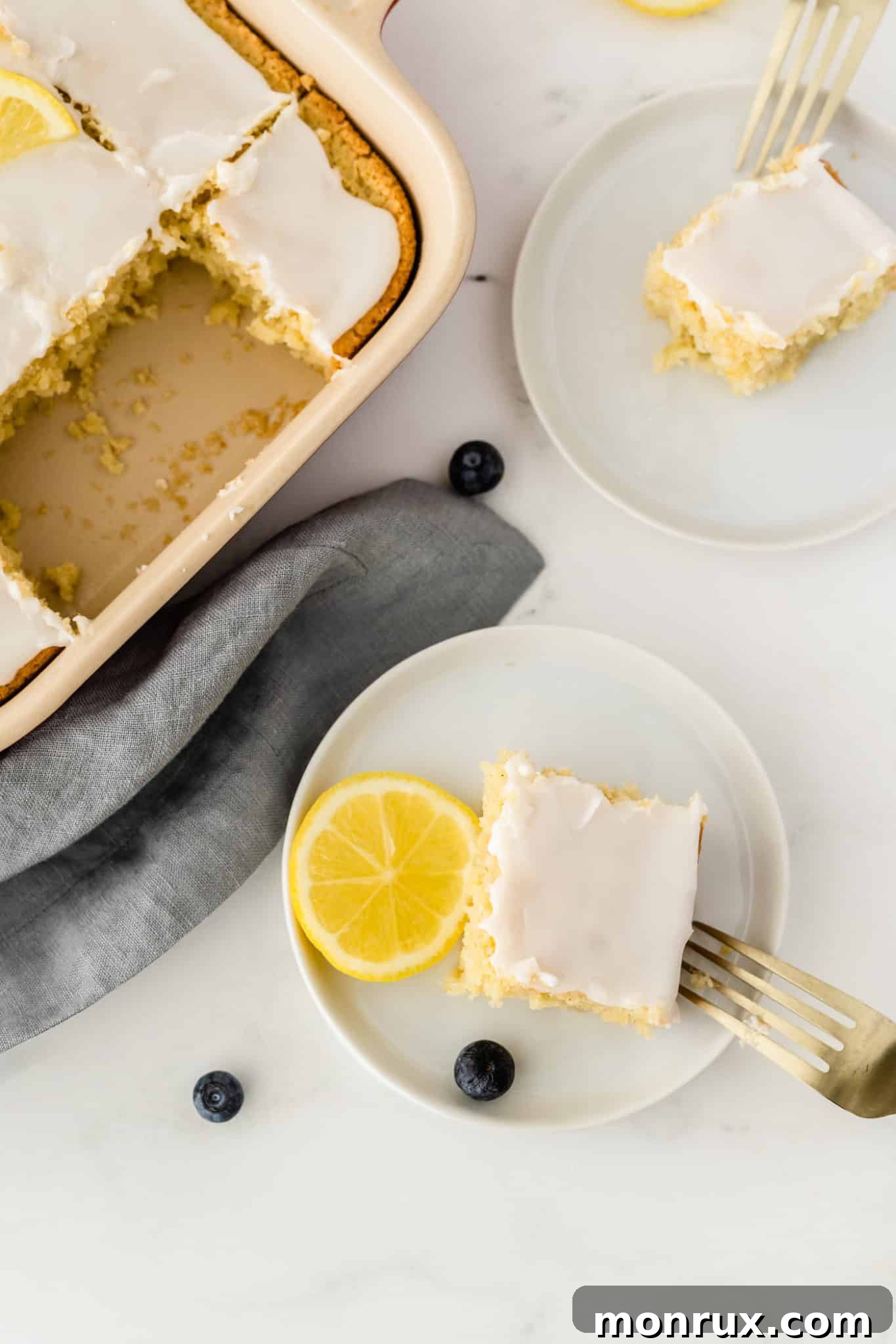 Multiple slices of gluten-free lemon cake elegantly arranged on white plates, showcasing the moist interior and zesty drizzle.